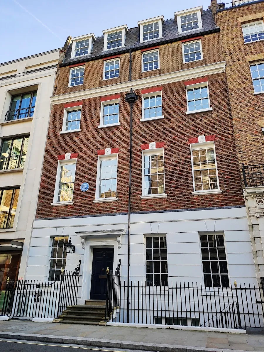 The Georgian brick and white stucco front of 3 Savile Row, with a round blue plaque mounted between two upper-floor windows