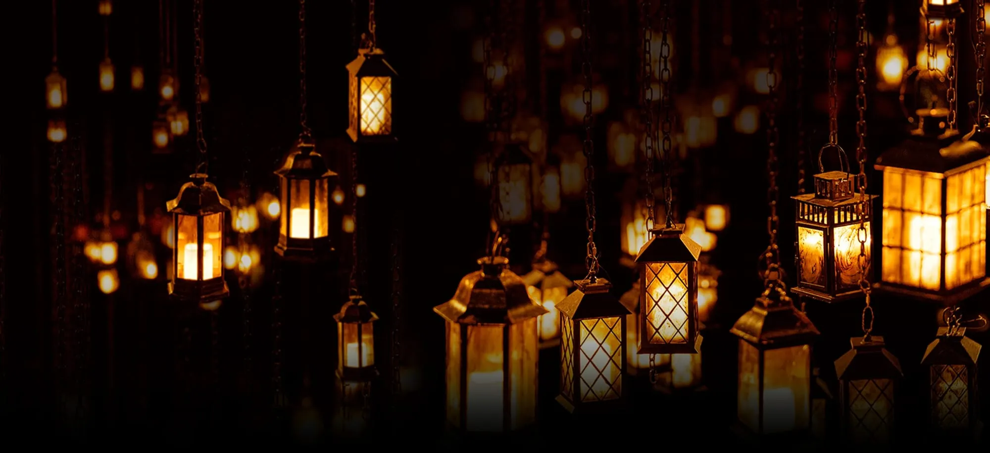 Rows of lit lanterns hanging on chains in the dark, the staging used for A Christmas Carol at the Old Vic