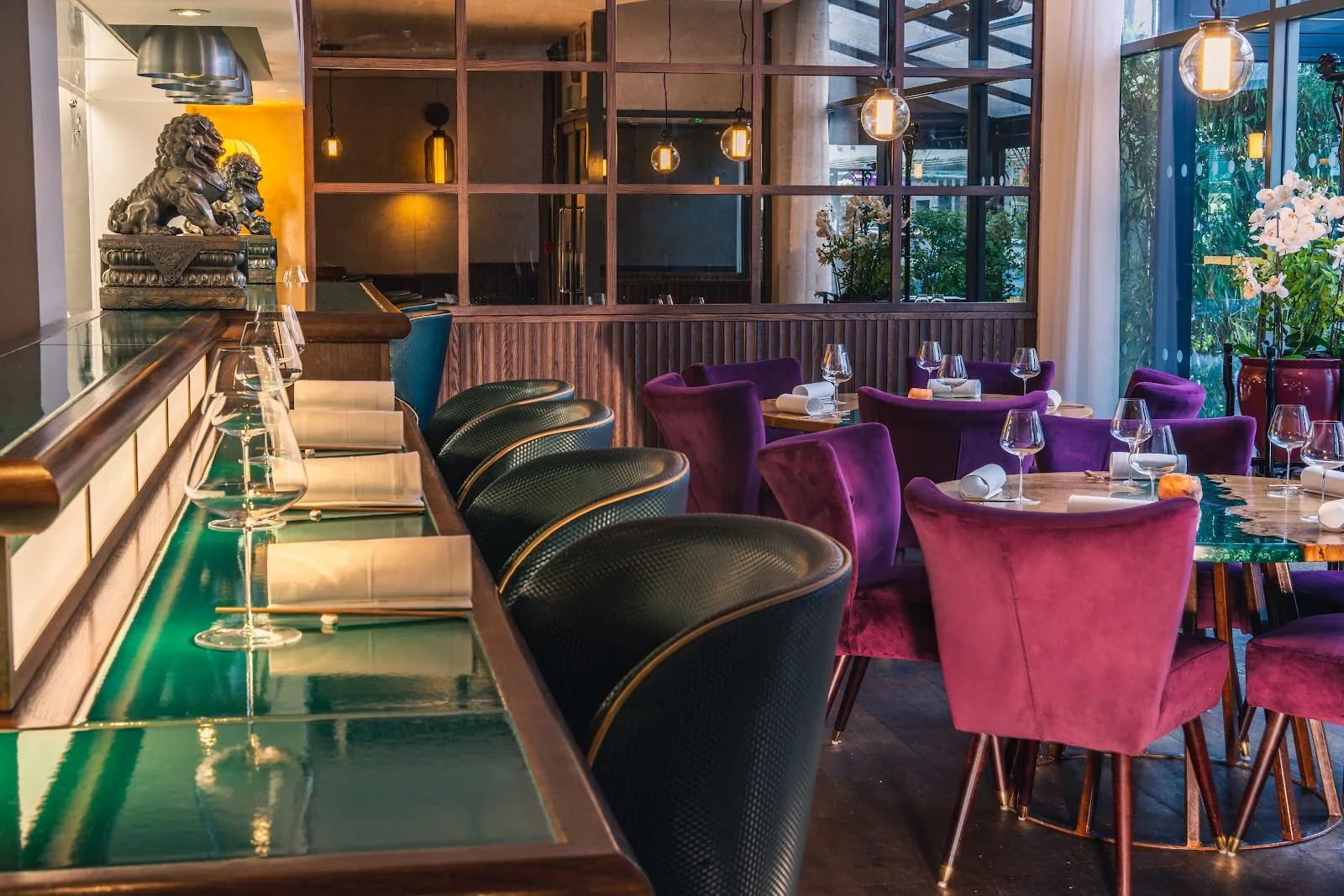 A. Wong's dining room with purple and burgundy velvet chairs, a green marble bar and a bronze guardian lion statue