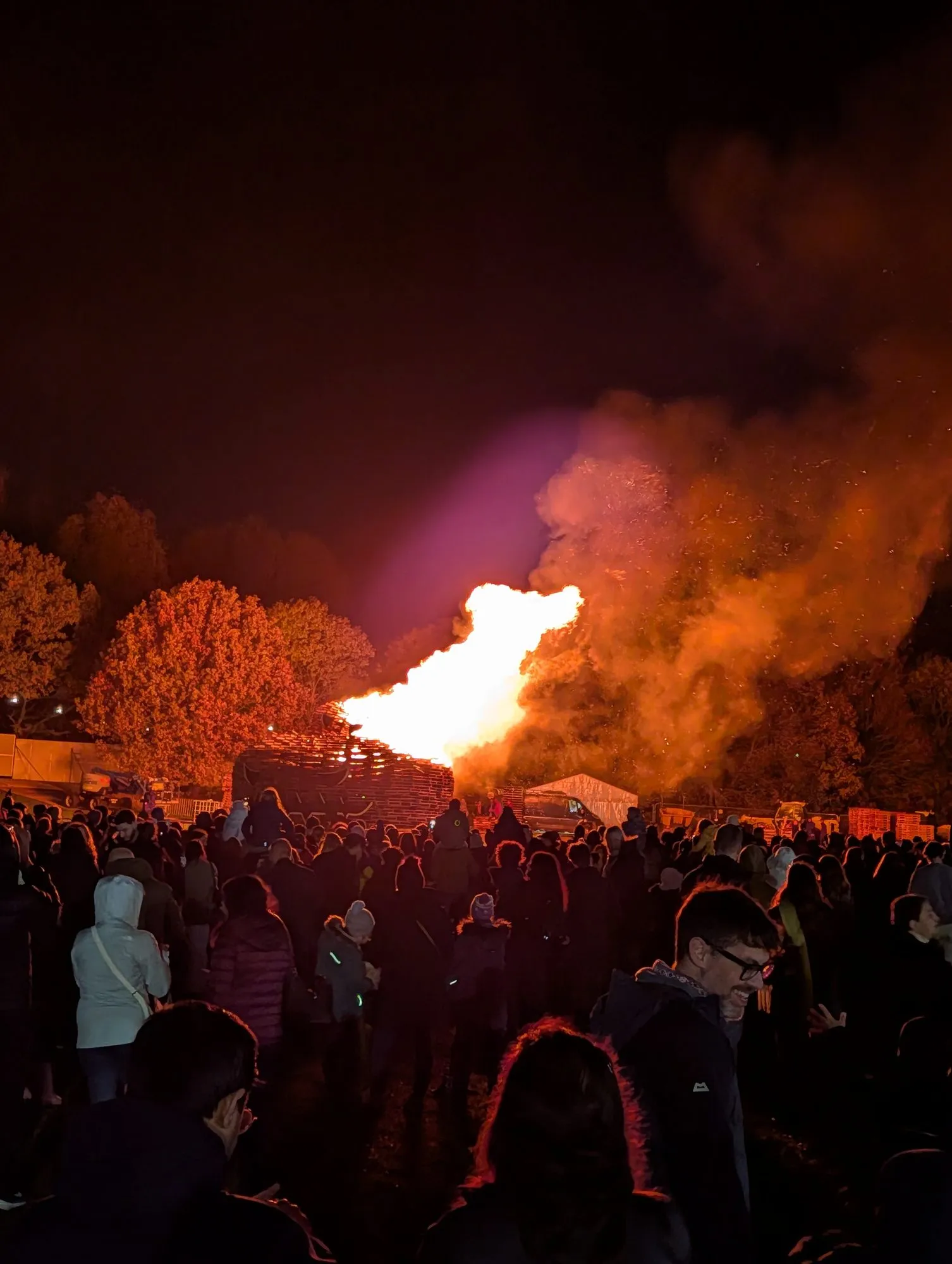 The Alexandra Palace bonfire fully ablaze, with a large crowd silhouetted against the flames