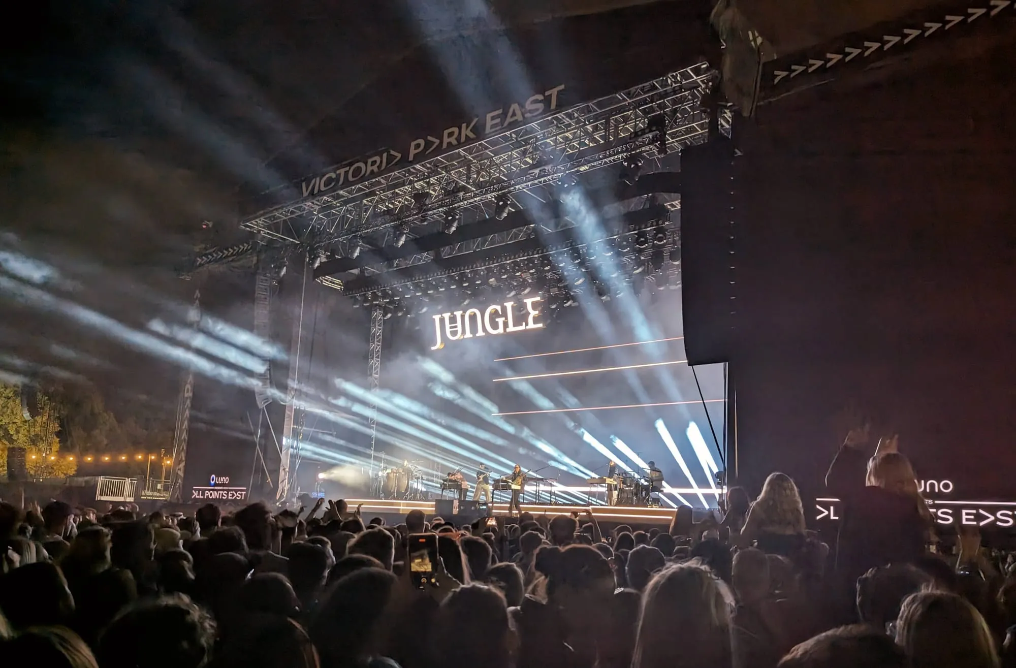 Jungle on the main stage at All Points East in Victoria Park at night, white light beams over a packed crowd