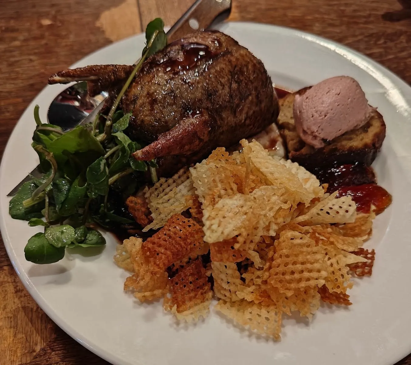 A roasted quail with crispy shoestring fries, watercress and a slice of pâté on toast, on a plate at Anchor & Hope