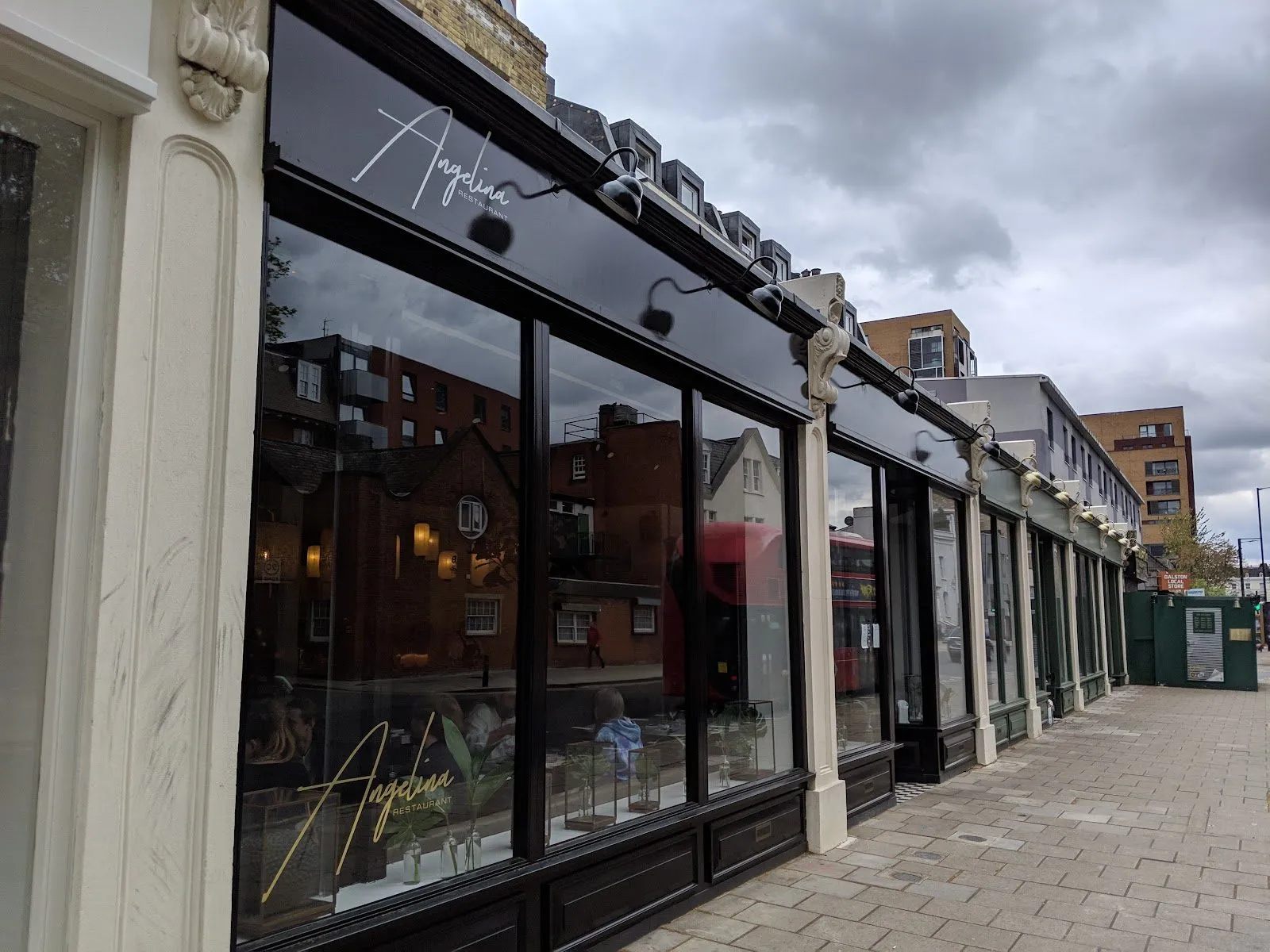 The black-fronted shopfront of Angelina on Dalston Lane, with the name in white script above the windows and gold script on the glass