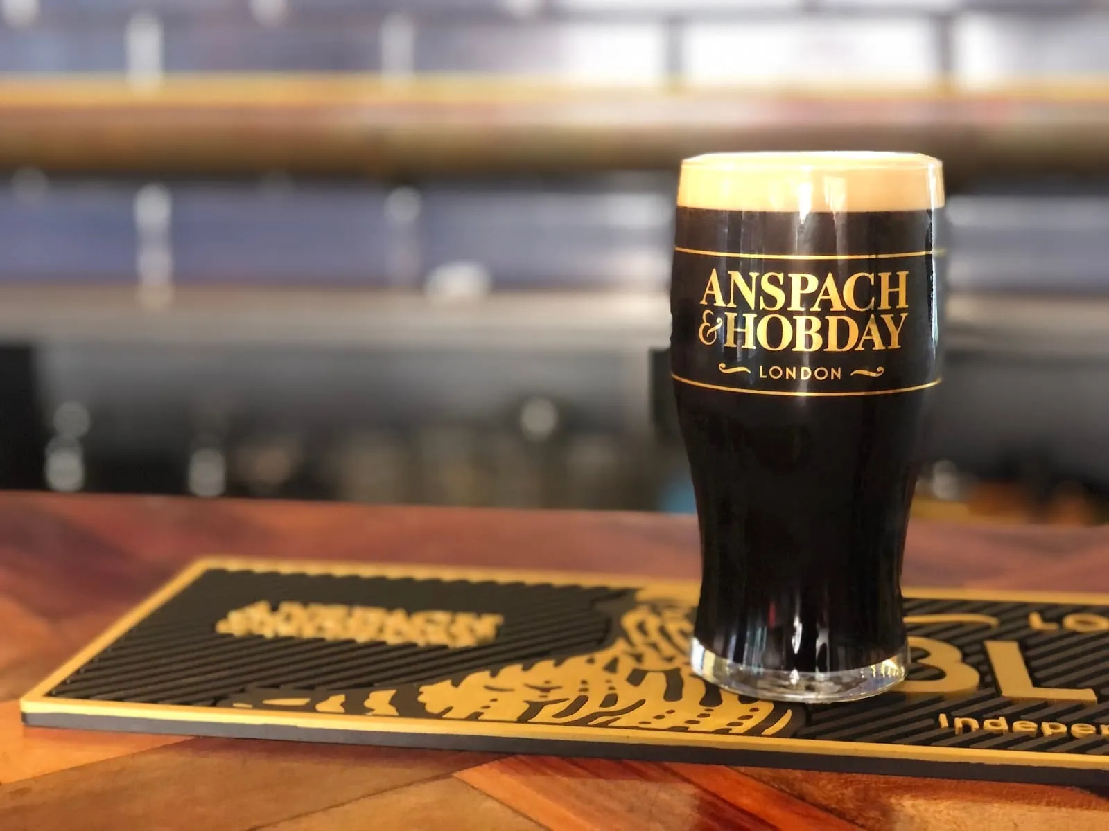 A branded Anspach & Hobday glass of dark beer on the bar at the Arch House taproom