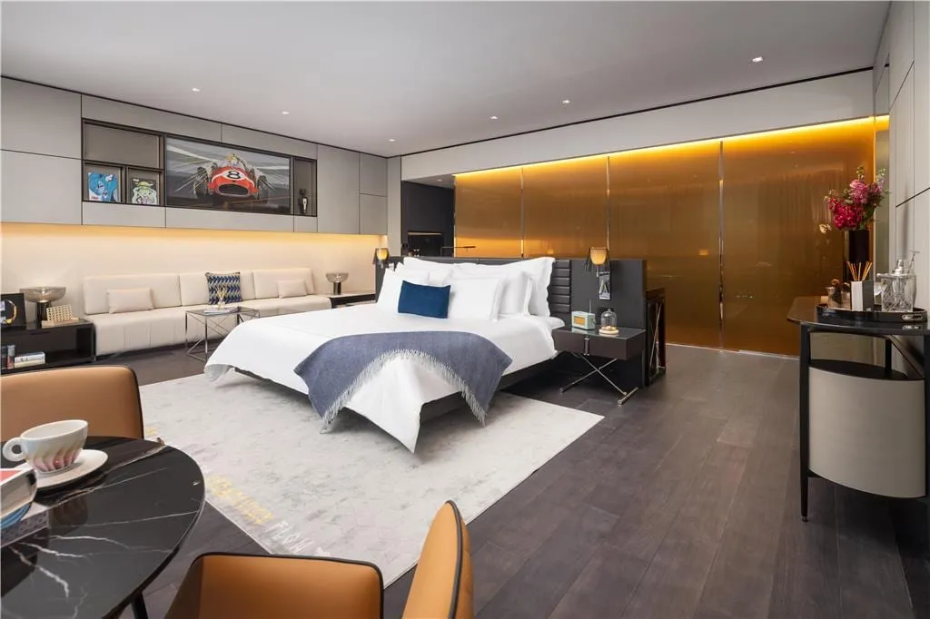 A room at art'otel London Hoxton, with D*Face artwork on the wall, amber glass panelling and a curved cream sofa