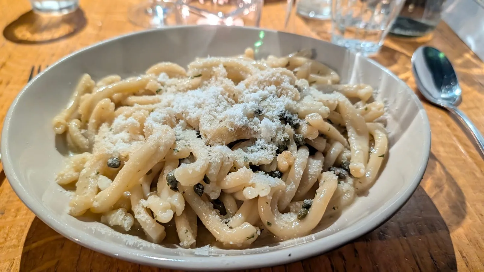 A plate of casarecce pasta with capers, dressed simply and finished with grated parmesan