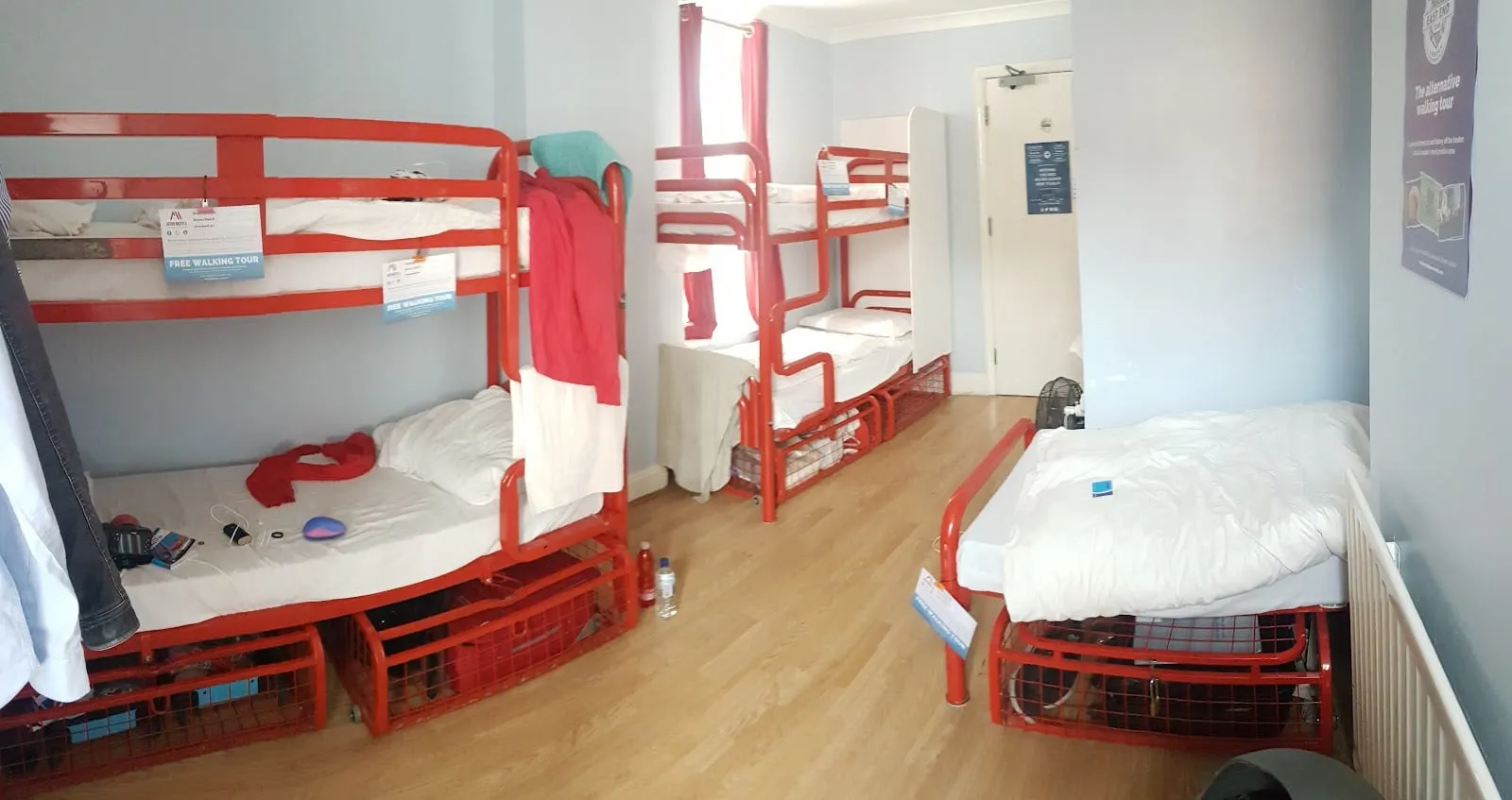 A shared dorm at Astor Hyde Park, with red-framed bunk beds and a tall sash window