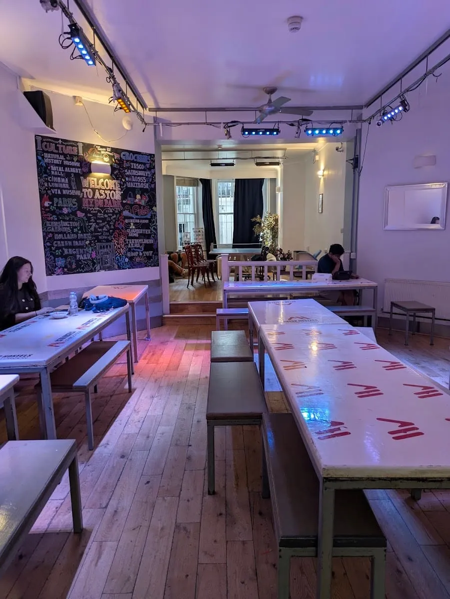 Astor Hyde Park's communal dining room, with a chalkboard mural reading "WELCOME TO ASTOR HYDE PARK" and listing nearby museums and parks