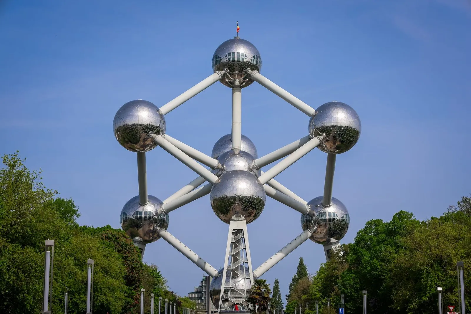 The Atomium's nine steel spheres and connecting tubes against a blue sky, seen from the avenue leading up to it