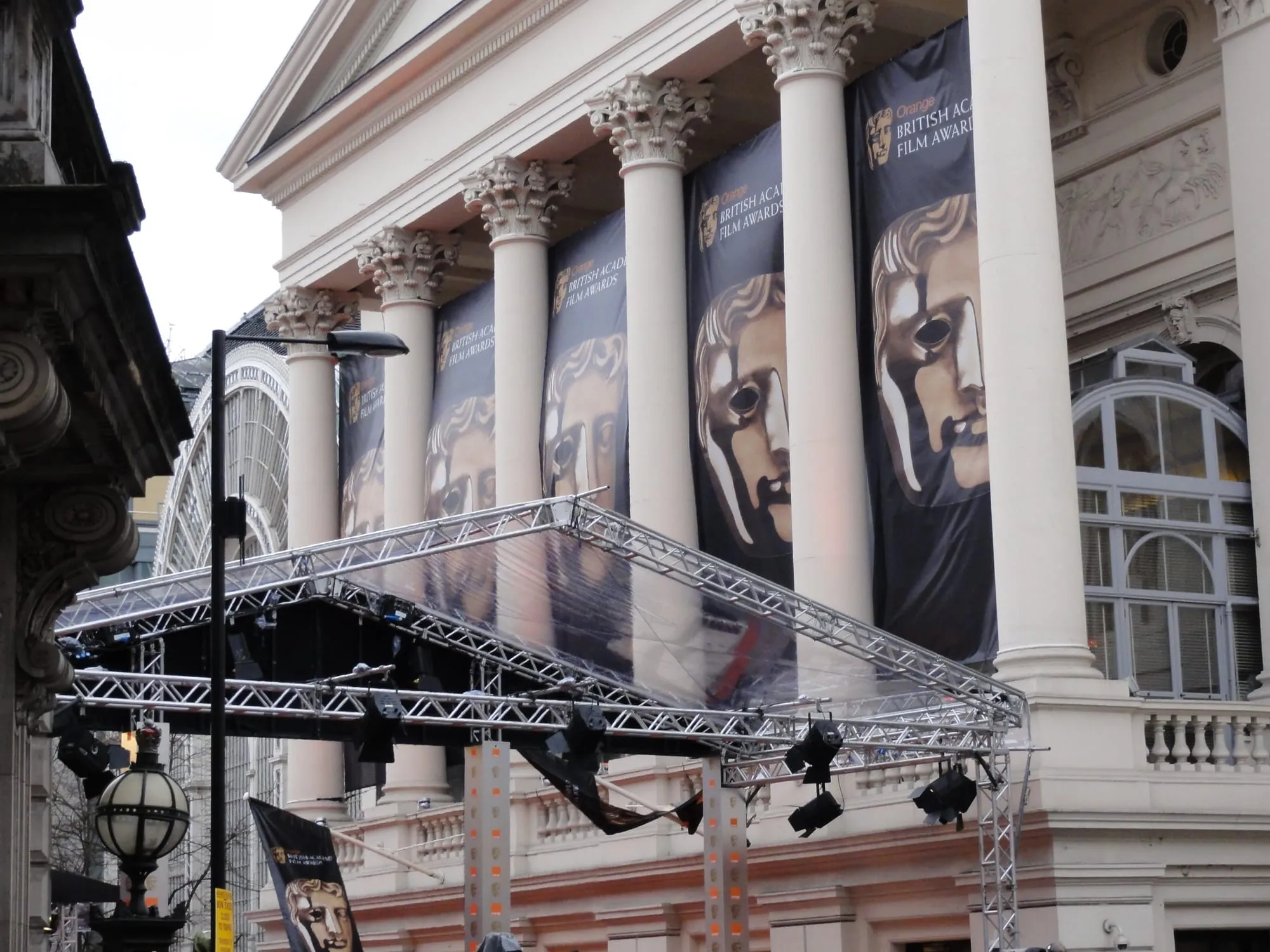 BAFTA mask banners hang between the columns of the Royal Opera House, with a glass-roofed red-carpet canopy built out over the pavement