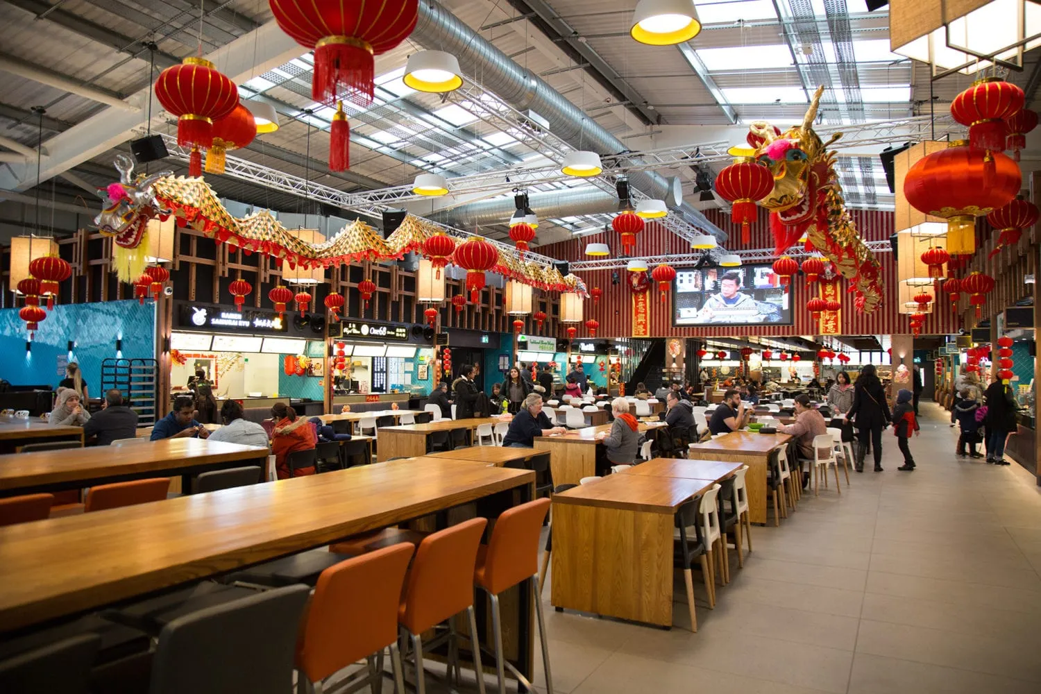 Inside Bang Bang Oriental food hall, with a large dragon and red lanterns hanging above rows of tables