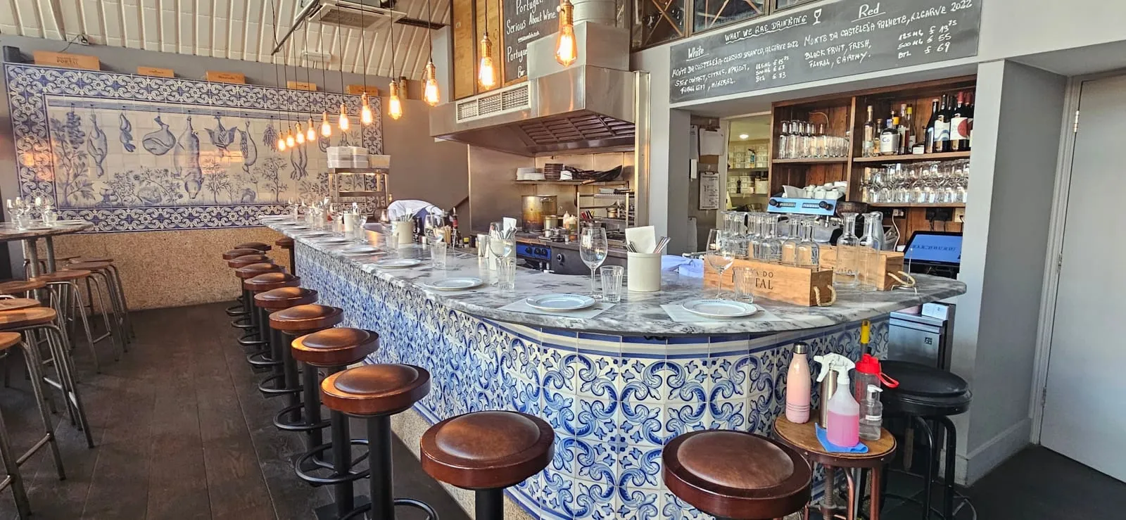 The counter at Bar Douro, faced in blue-and-white azulejo tiles with leather bar stools, under a slatted ceiling with a tiled panel on the back wall