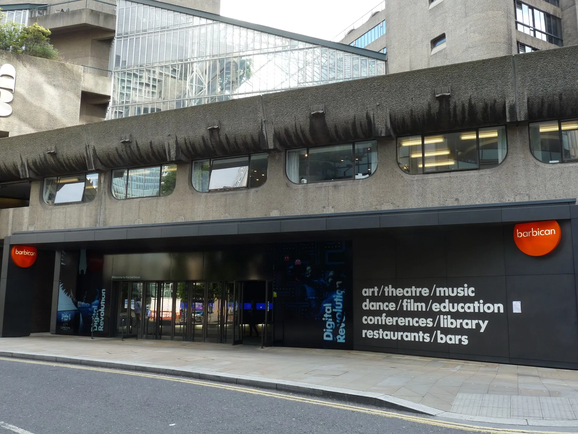 The Silk Street entrance to the Barbican Centre, concrete walkways and the centre's name in white lettering above the doors