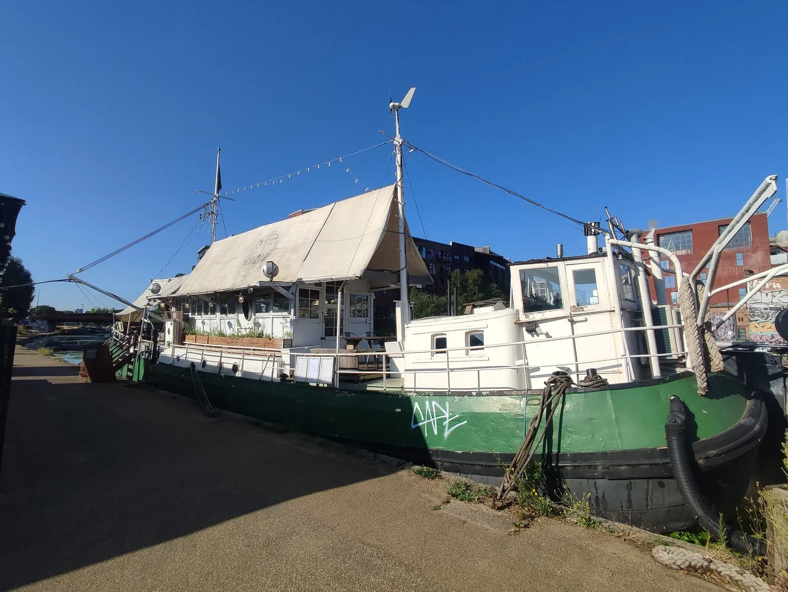 A converted Dutch barge moored on the River Lea with a canopied deck