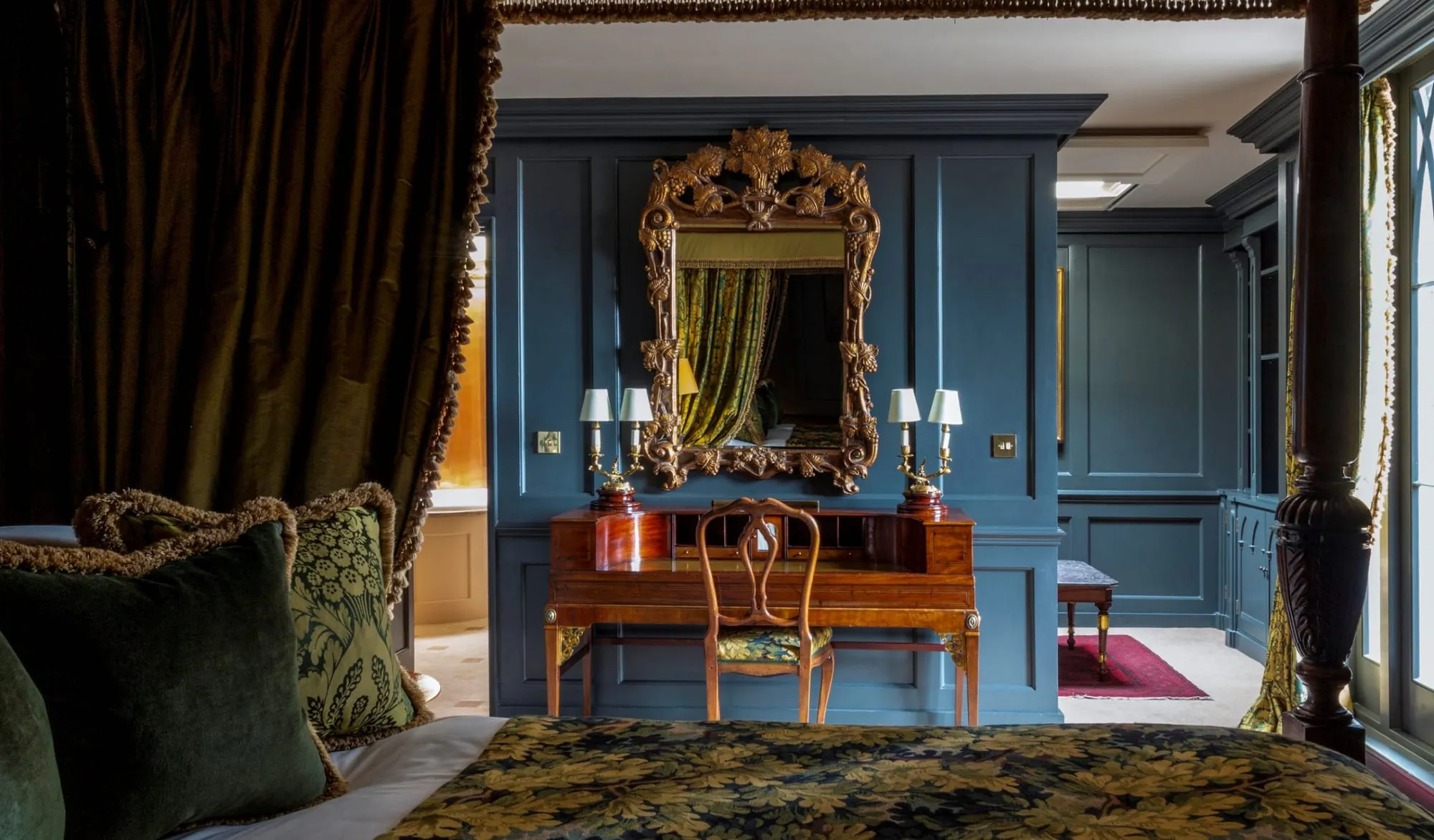 A room at Batty Langley's with dark wood panelling, a gilt-framed mirror and an antique writing desk