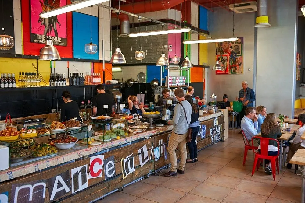 The counter at Beany Green, its bright painted walls and food display with customers queuing