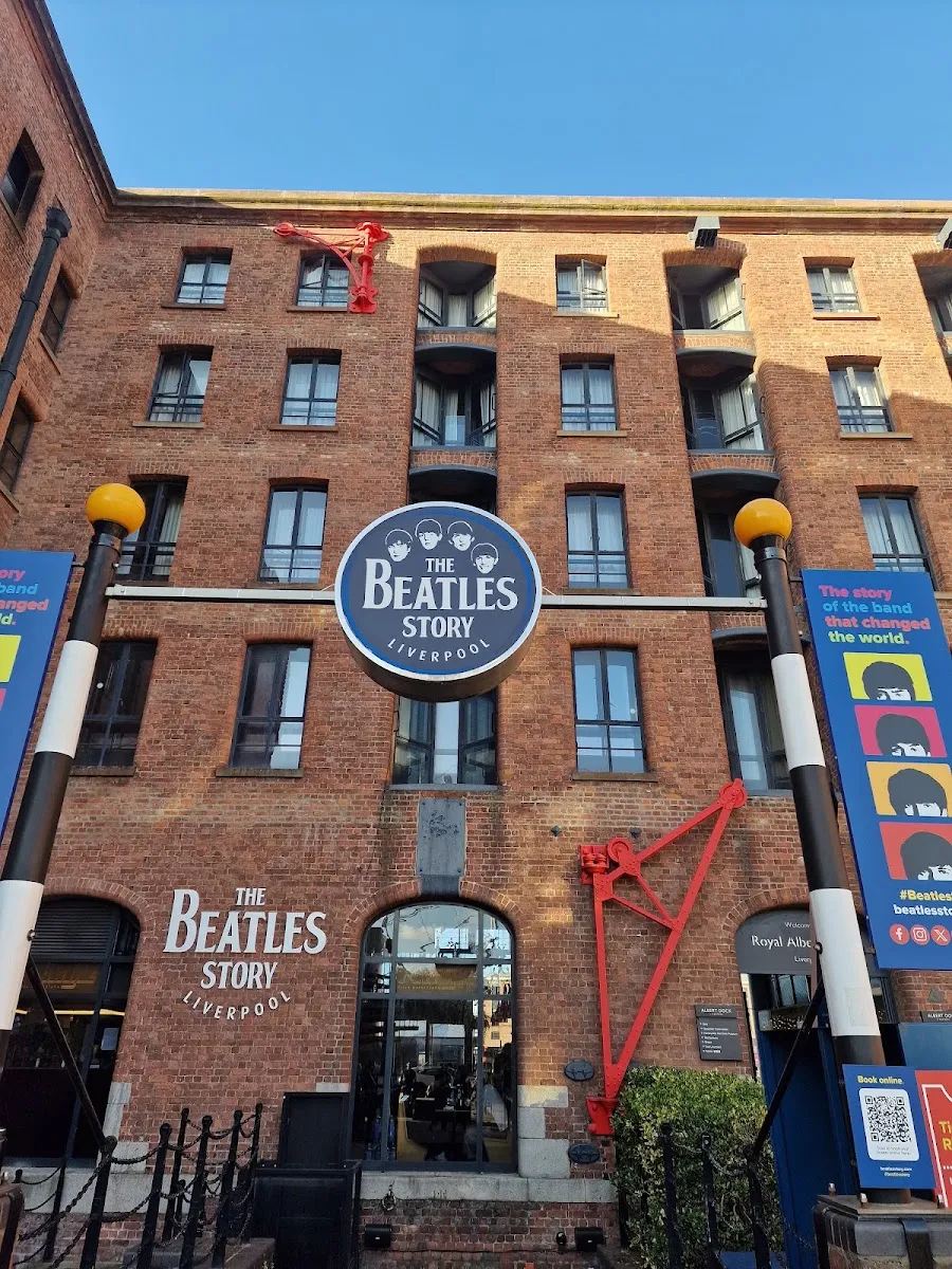 The Beatles Story's brick warehouse frontage at Royal Albert Dock, with a large circular sign above the entrance and banners either side