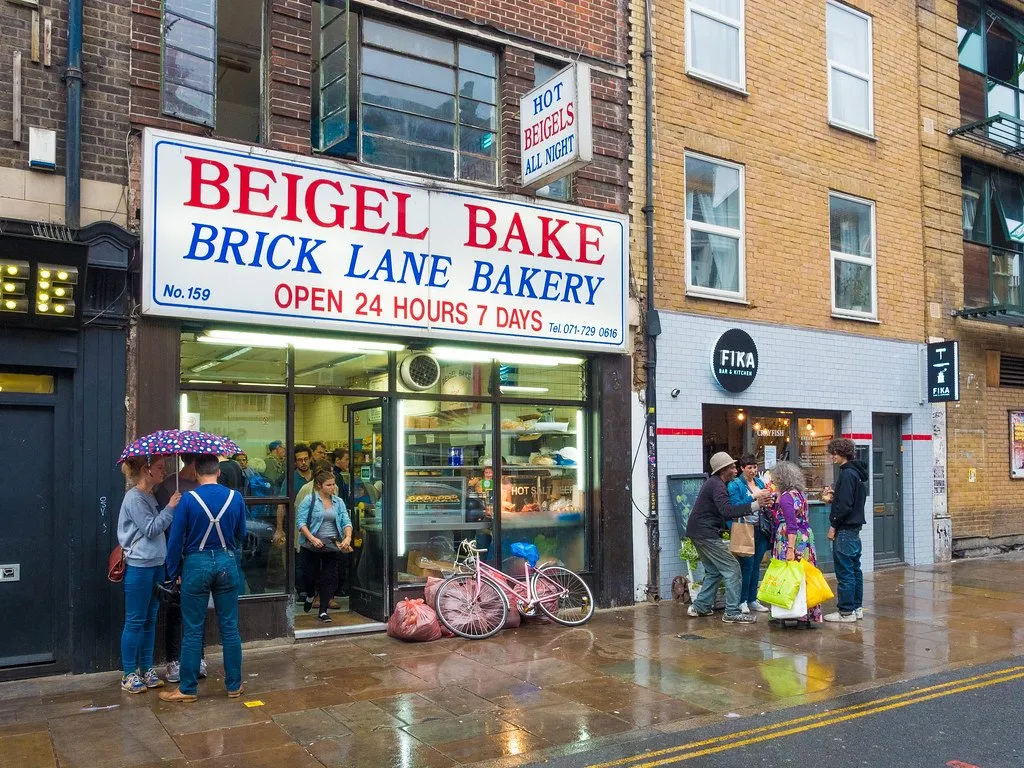 Customers outside the Beigel Bake shopfront on Brick Lane in the rain