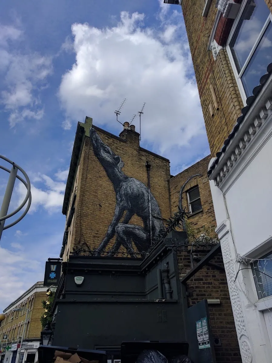 A large mural of a fox painted on the side of a building on Bellenden Road, against a blue sky