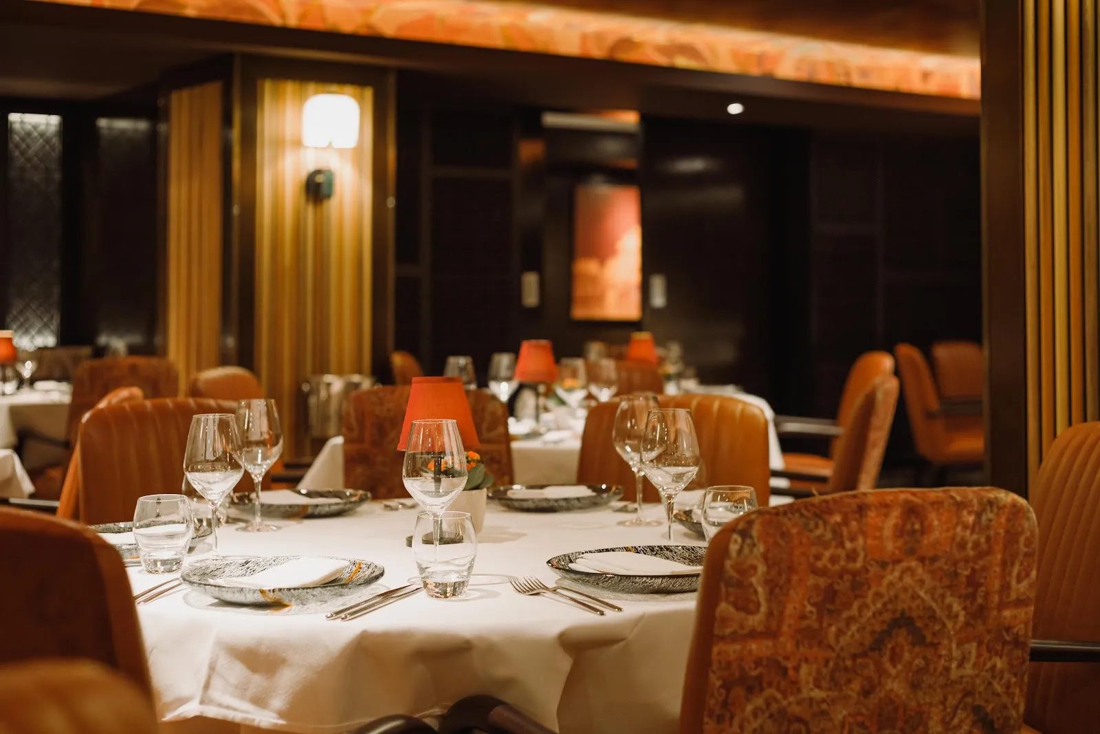 The dining room at Benares on Berkeley Square with white linen tables, leather armchairs and soft lamplight
