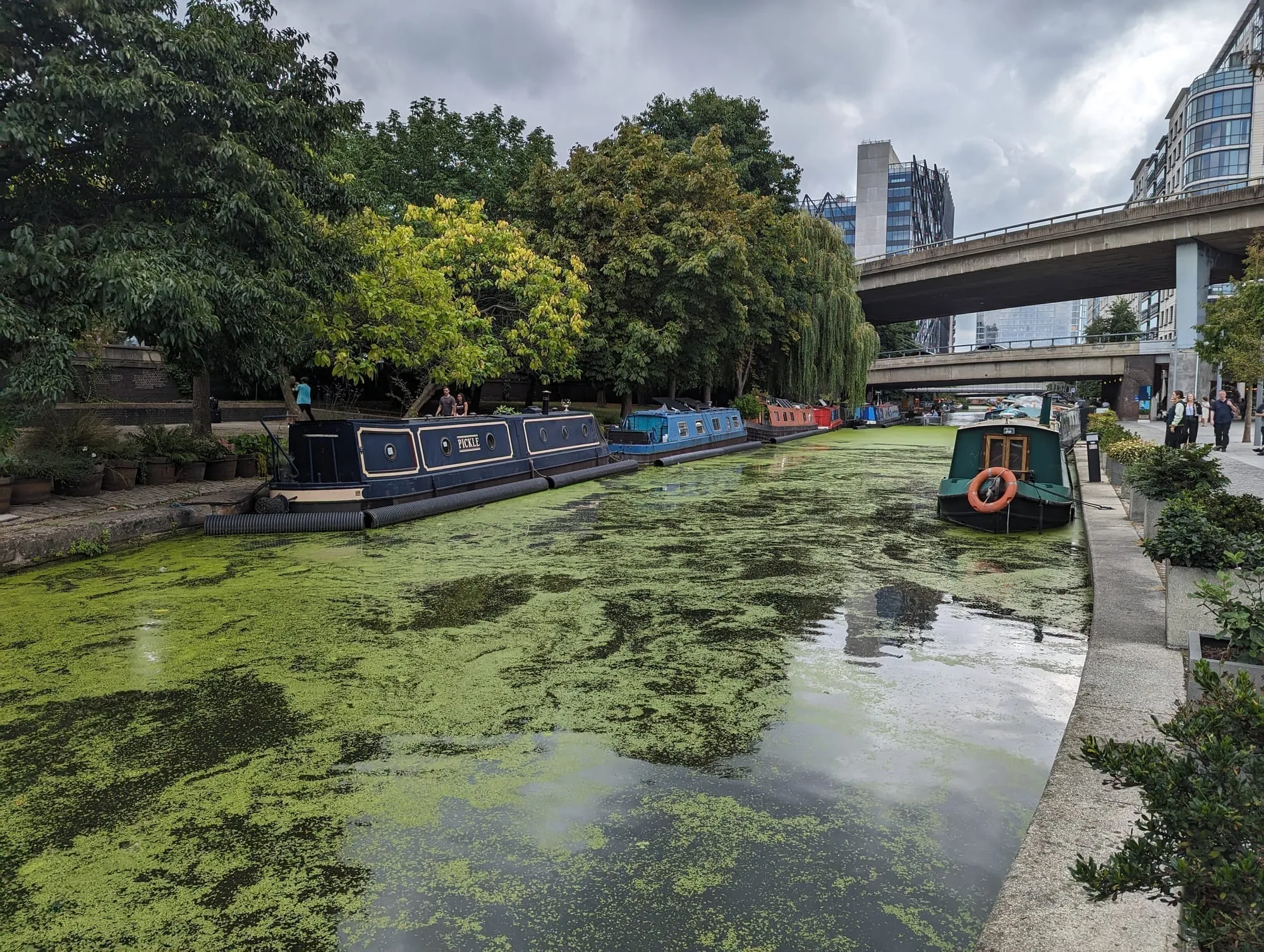 Narrowboats moored along the Paddington Arm of the Grand Union Canal, with the Westway flyover crossing behind
