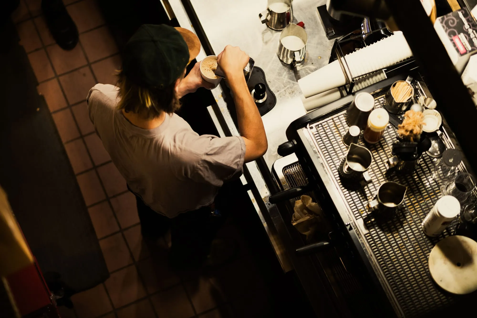A barista working at an espresso machine, seen from above