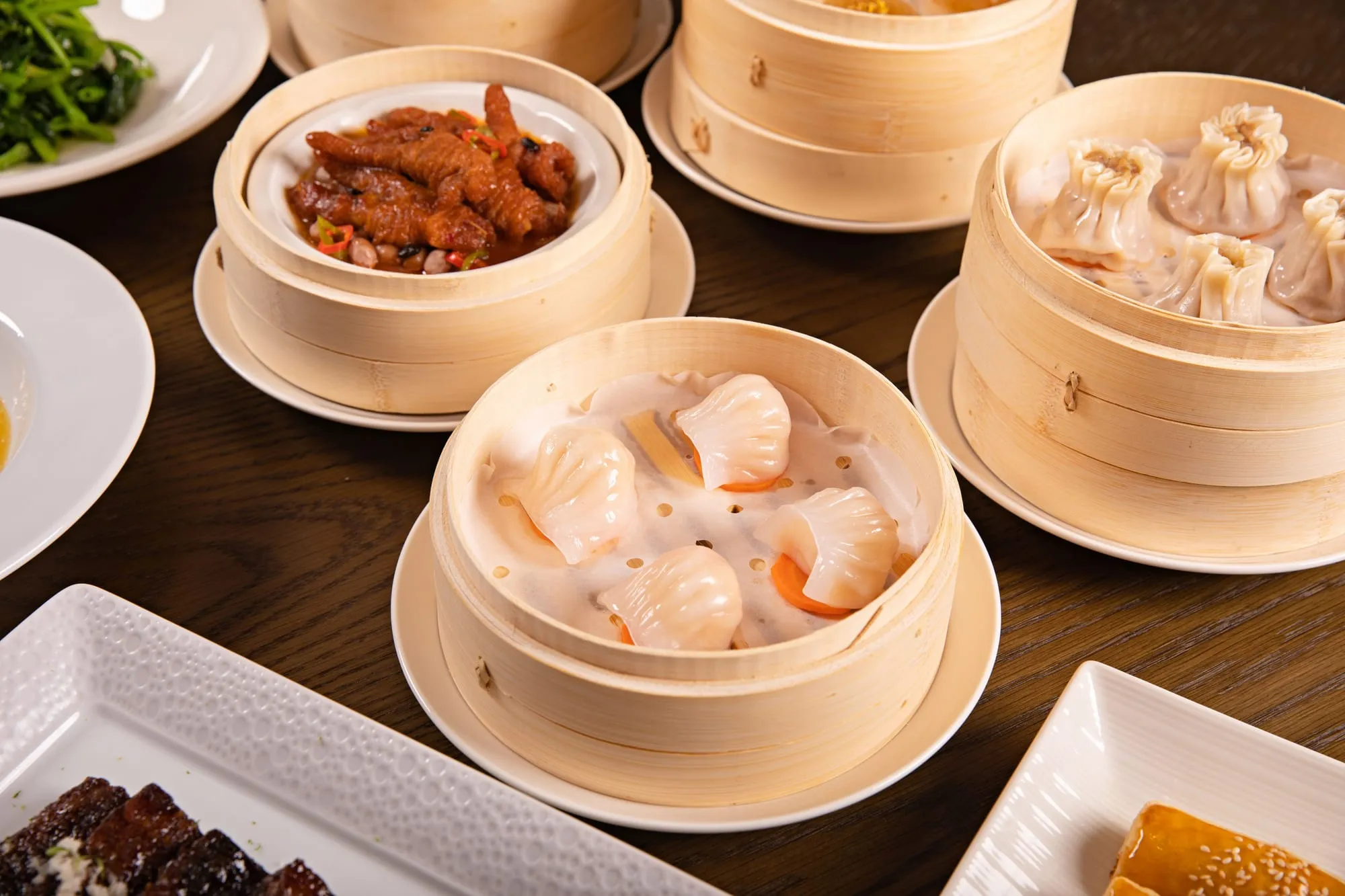 Bamboo steamers of prawn dumplings and other dim sum on a dark table