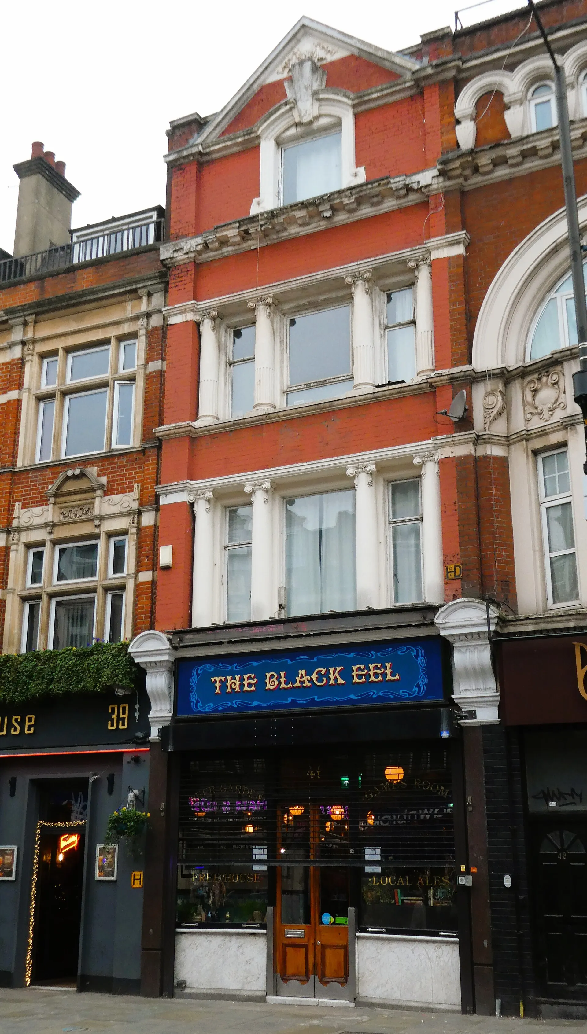 The Black Eel's narrow red-brick frontage on Kingsland High Street, with a blue and gold painted sign over the old shopfront
