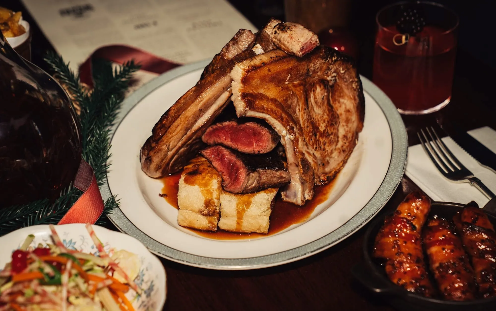 A bone-in chop at Blacklock, carved at the table, with confit potato and bacon-wrapped sausages alongside