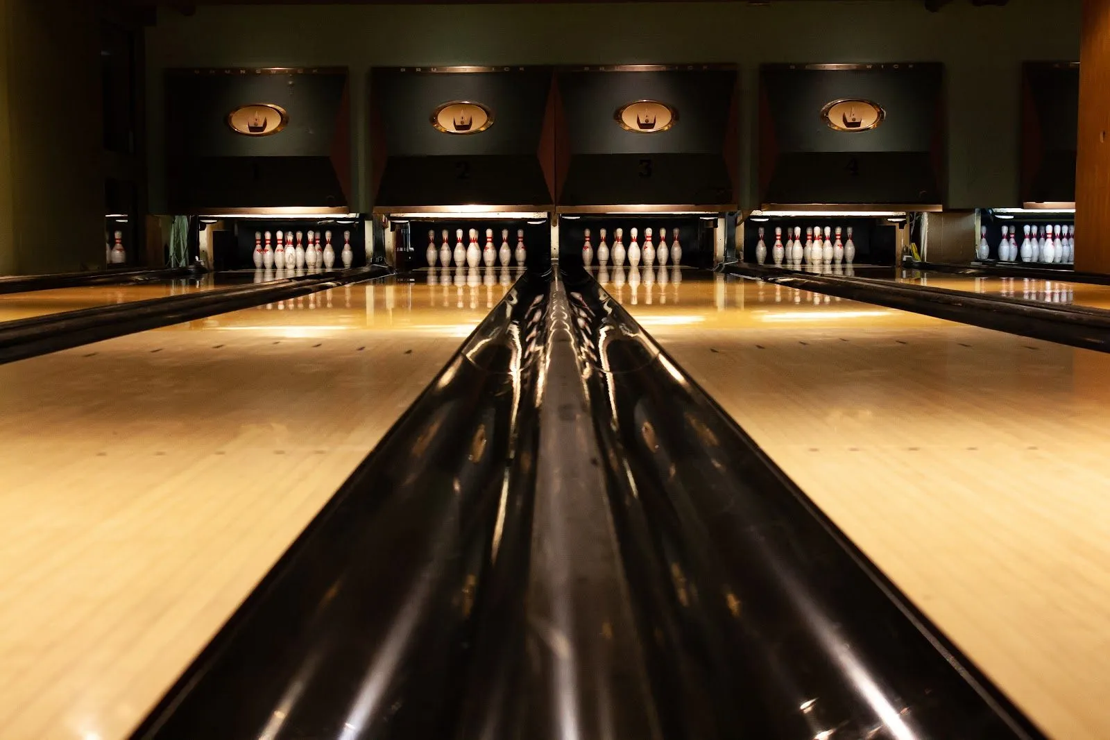 Bloomsbury Lanes' bowling lanes 1 to 4, polished wood running to the pins under a lit mask above each lane