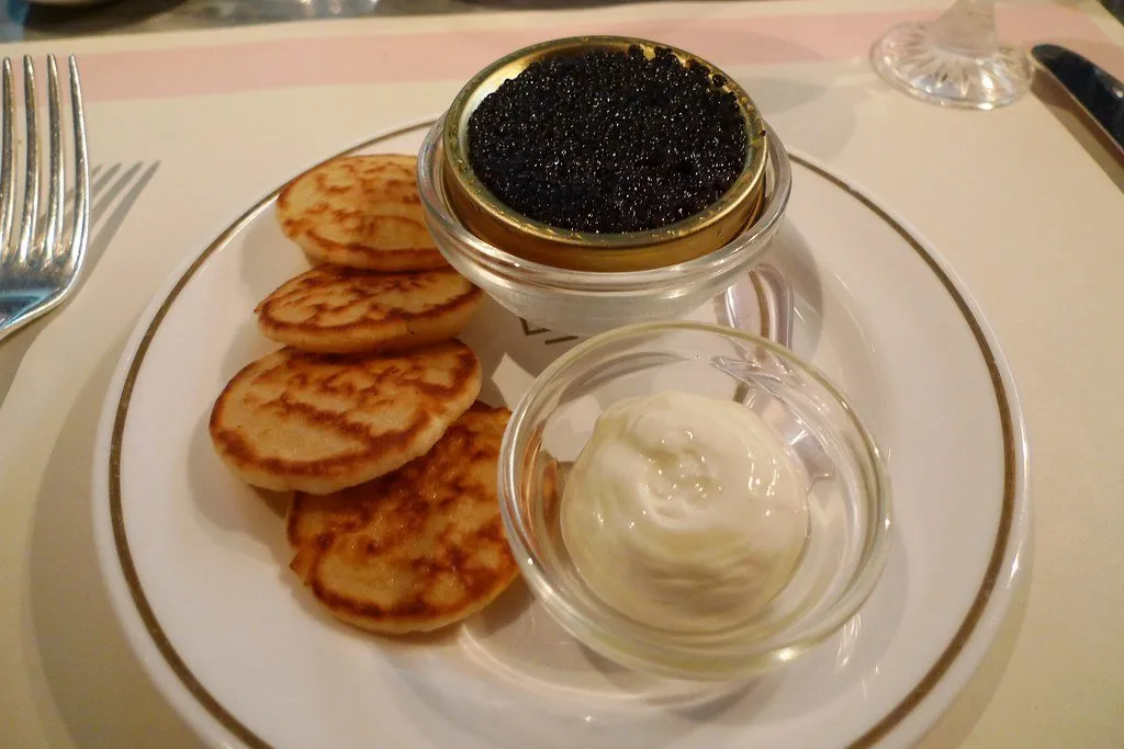Blinis with caviar and soured cream on a gold-rimmed plate