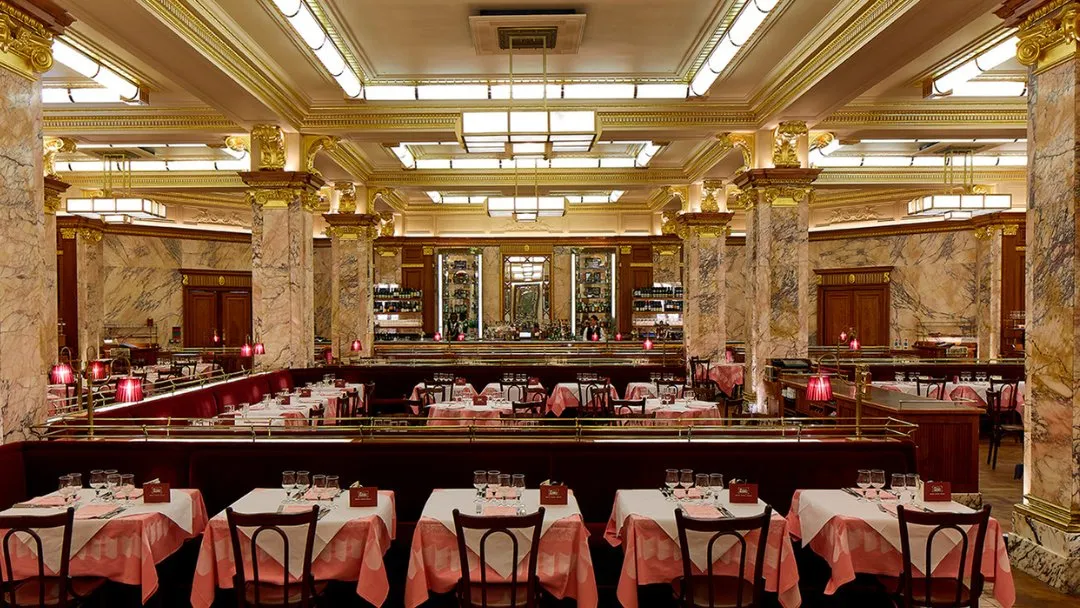 The gilded Art Deco dining room at Brasserie Zédel, with marble columns and tables laid with pink cloths