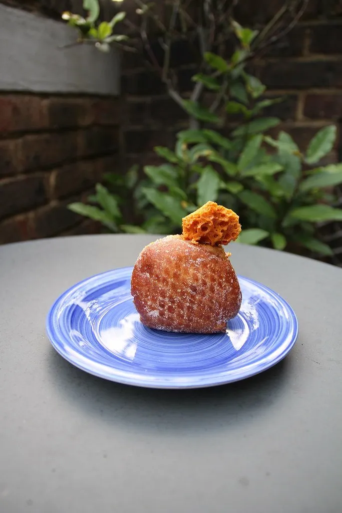 A sugar-dusted doughnut with a honeycomb shard on a blue plate