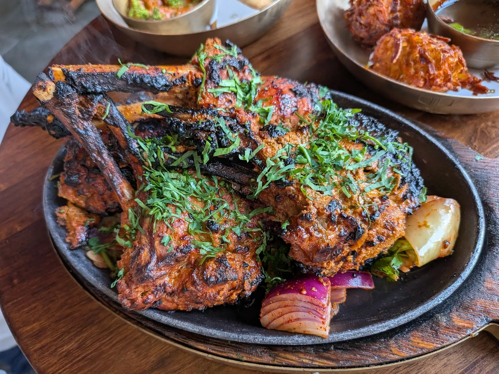 A sizzling platter of tandoori lamb chops and mixed grill with fresh coriander over spiced red onions at Brigadiers