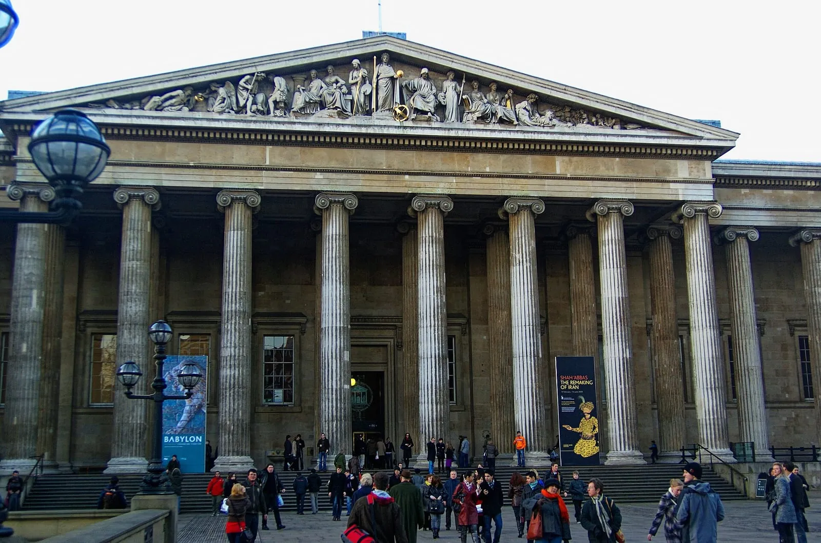 The Ionic columns and sculpted pediment of the British Museum's Great Russell Street front, with visitors on the steps