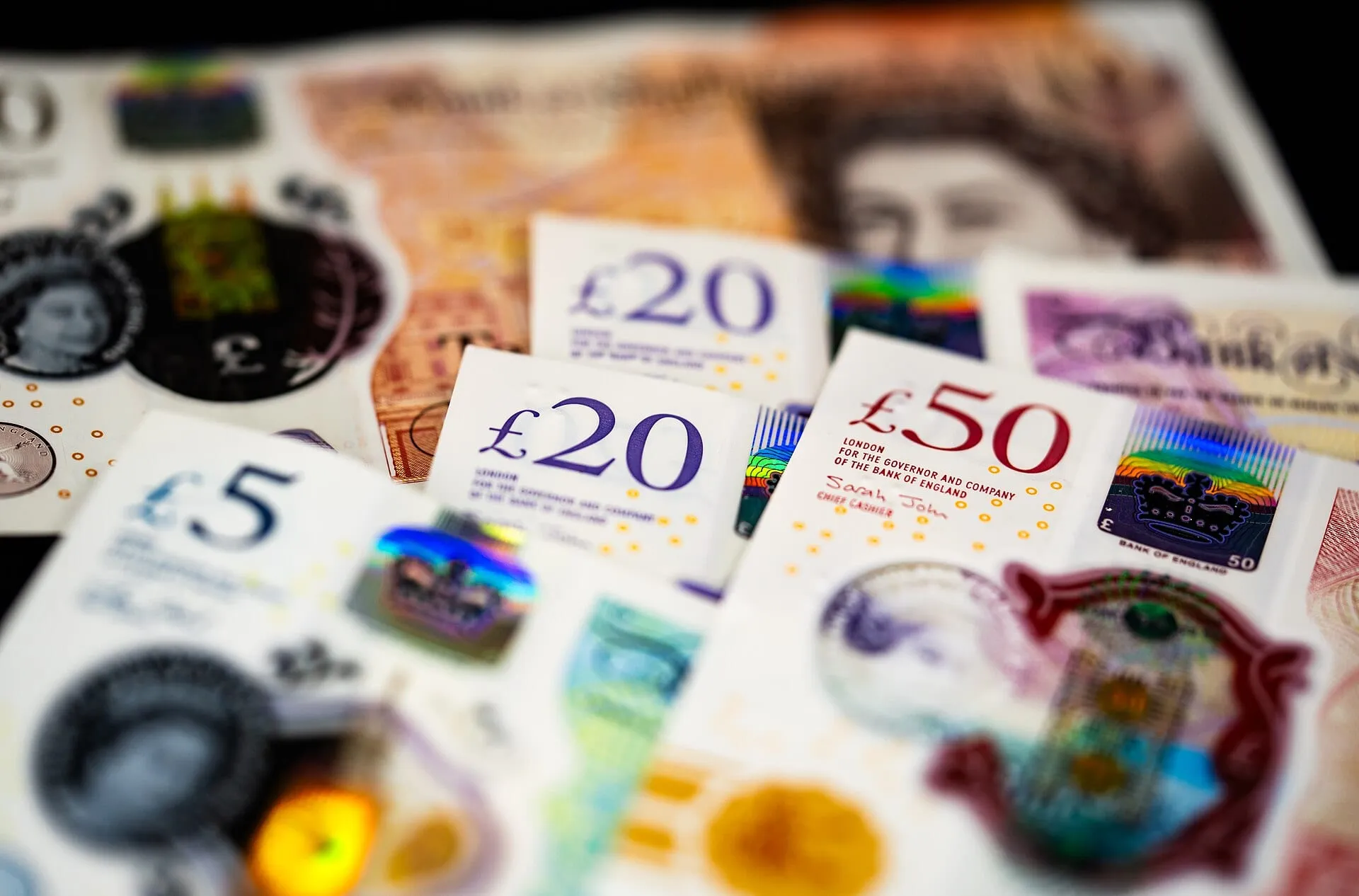 A selection of Bank of England polymer banknotes including £5, £20 and £50 notes showing holographic windows and security foil patches