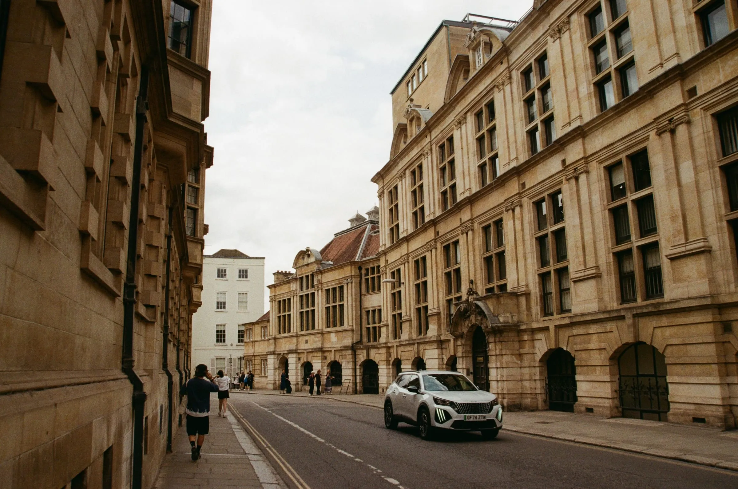 Broad Street in Oxford, the Clarendon Building and Sheldonian railings on the right and a car passing on the empty street