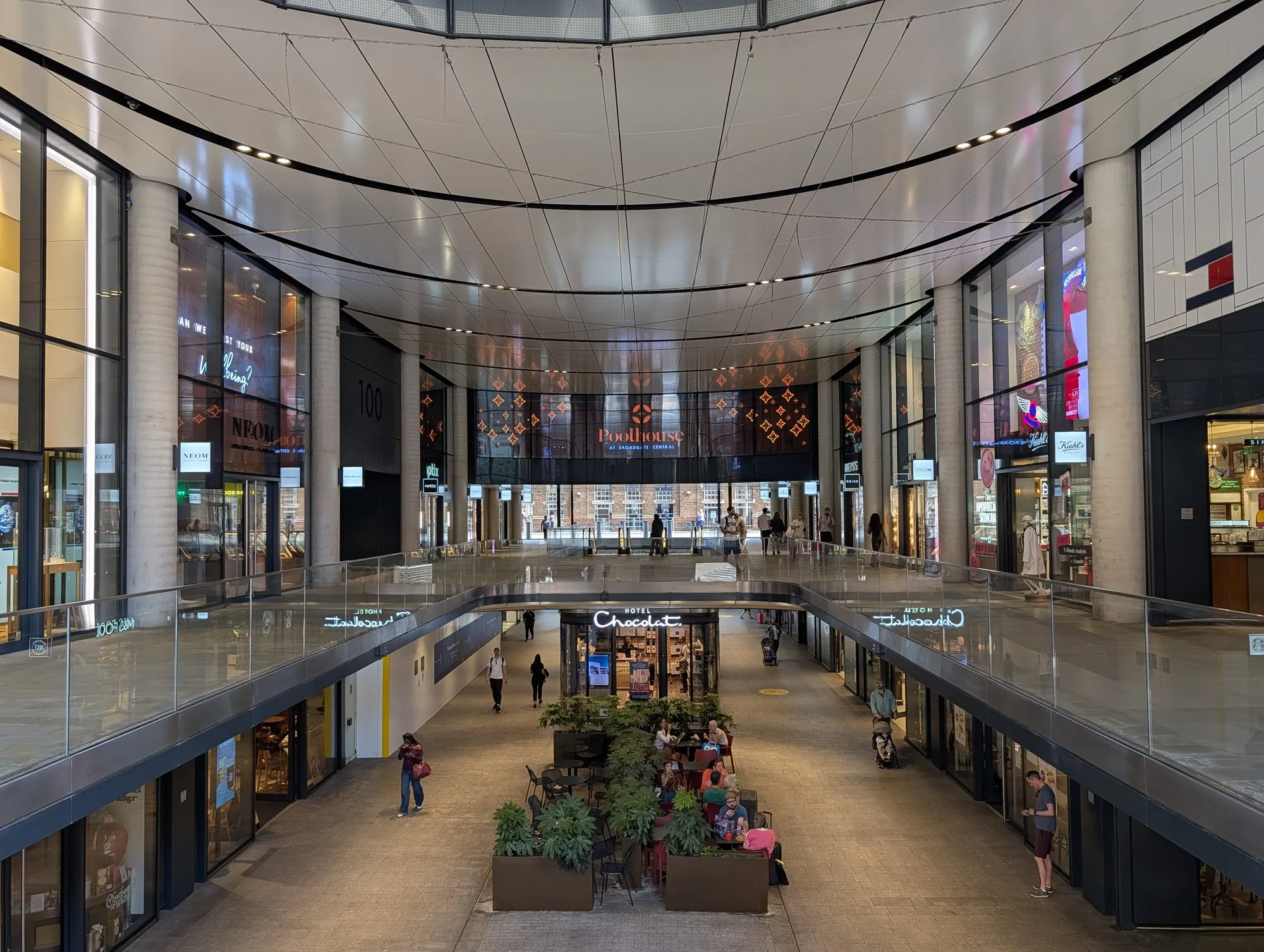 The covered arcade at Broadgate Central, with shops on two levels and tables on the lower walkway