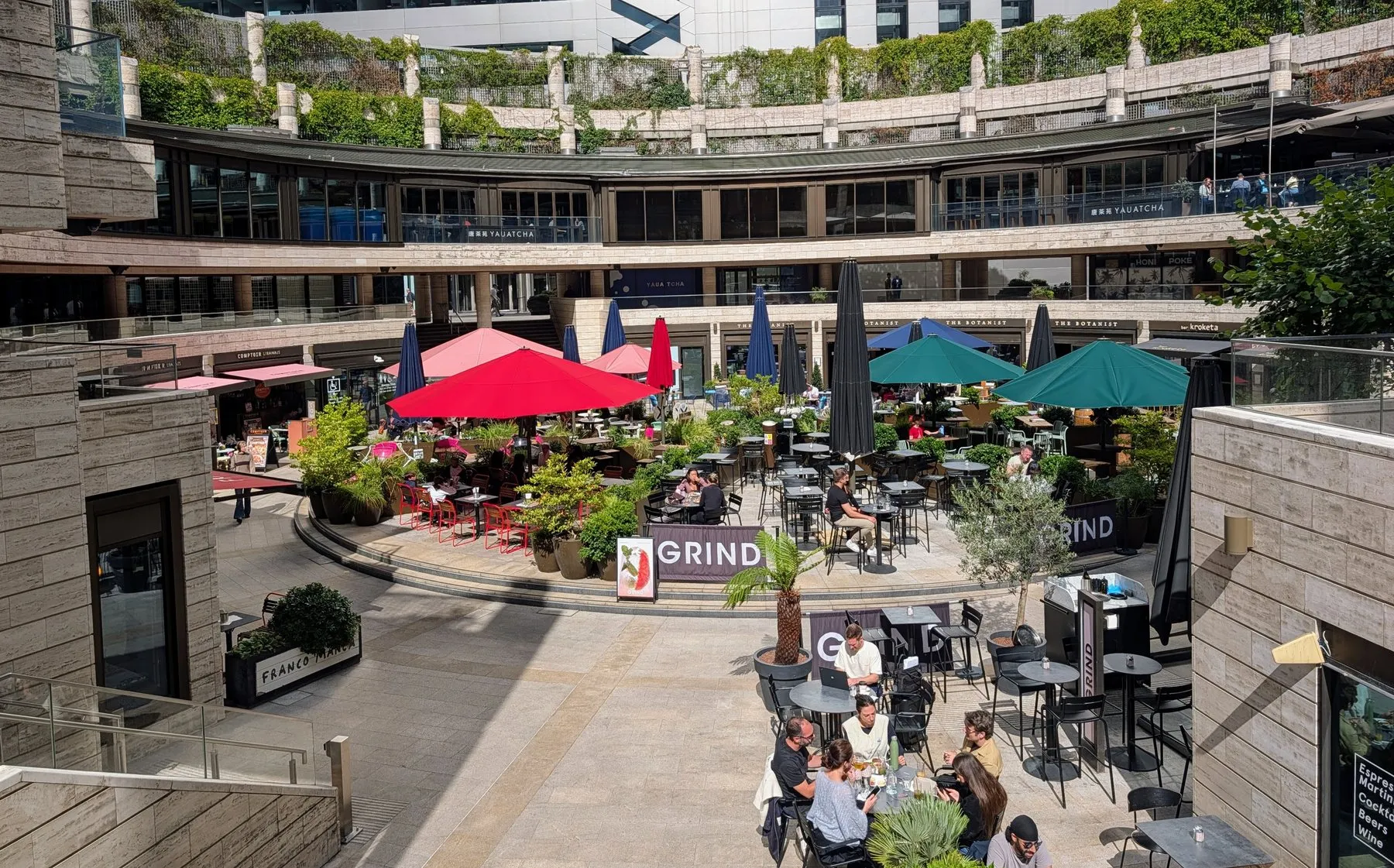 The sunken circular plaza of Broadgate Circle from above, ringed with restaurant terraces and coloured parasols