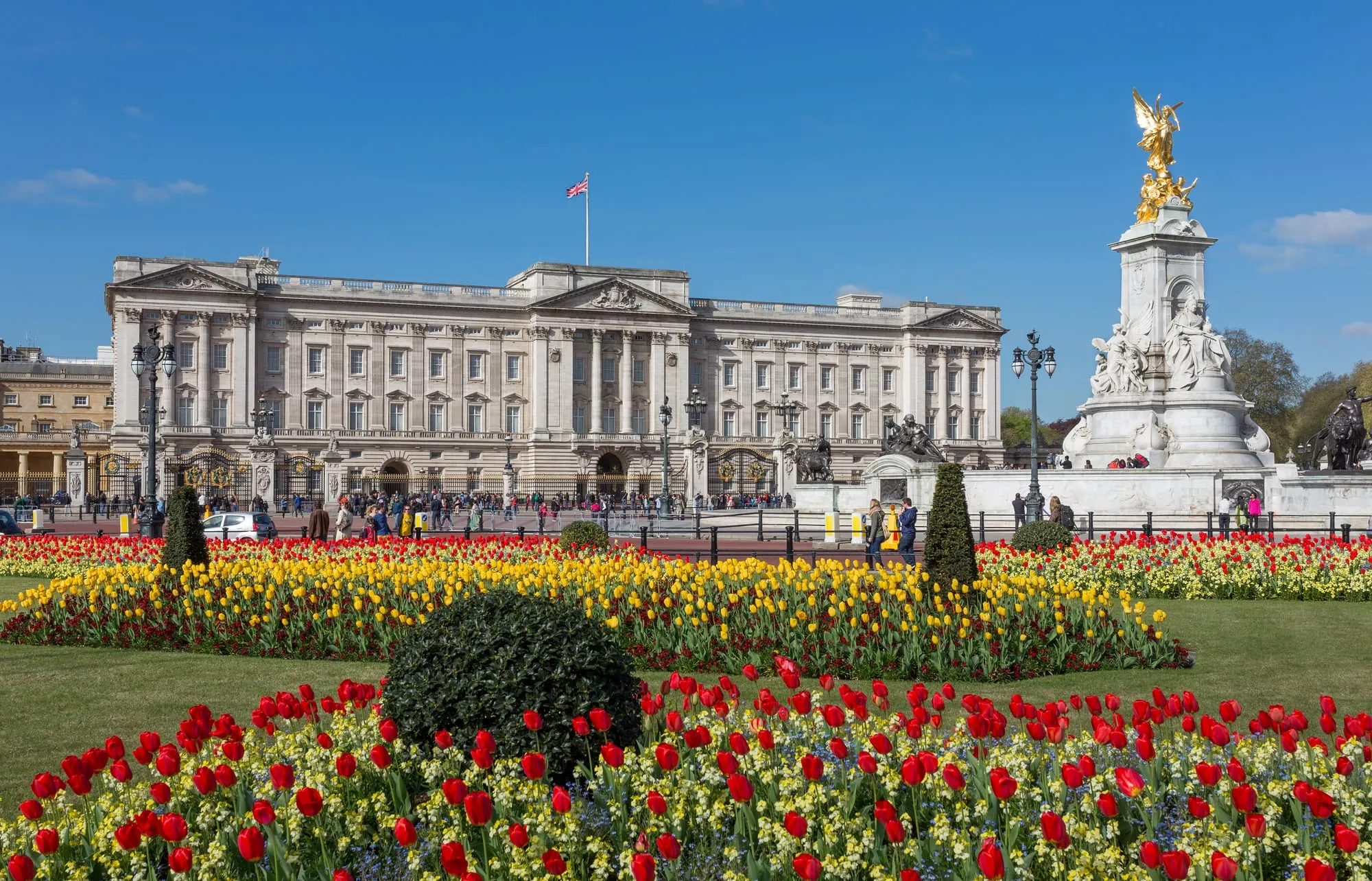 The East Front of Buckingham Palace and the gilded Queen Victoria Memorial seen across the spring flowerbeds of the Memorial Gardens