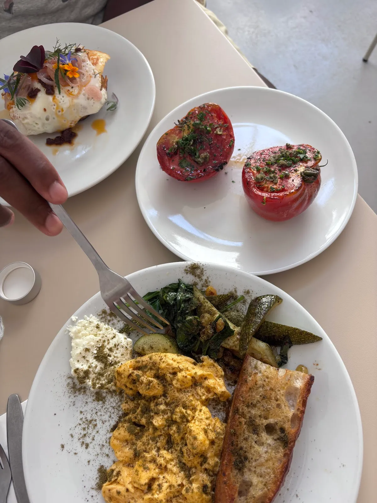 A brunch plate of spiced scrambled eggs with roasted tomato halves and sautéed greens at Burnt Arches
