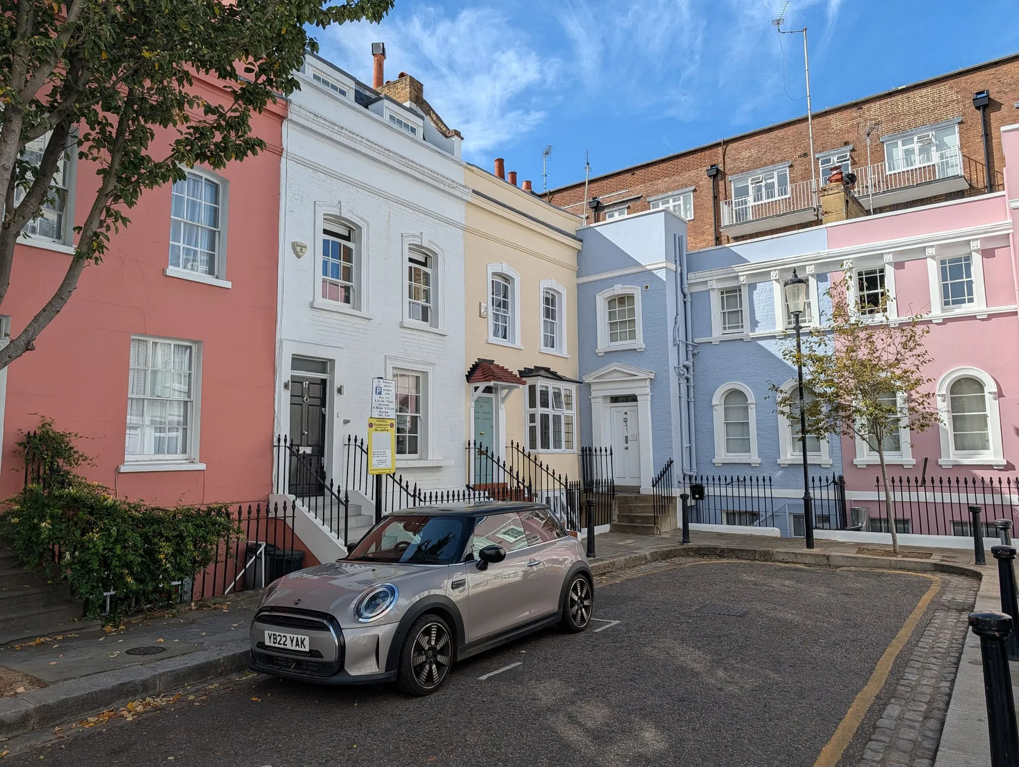 A terrace on Bywater Street painted pink, white and pale blue, with a car parked outside