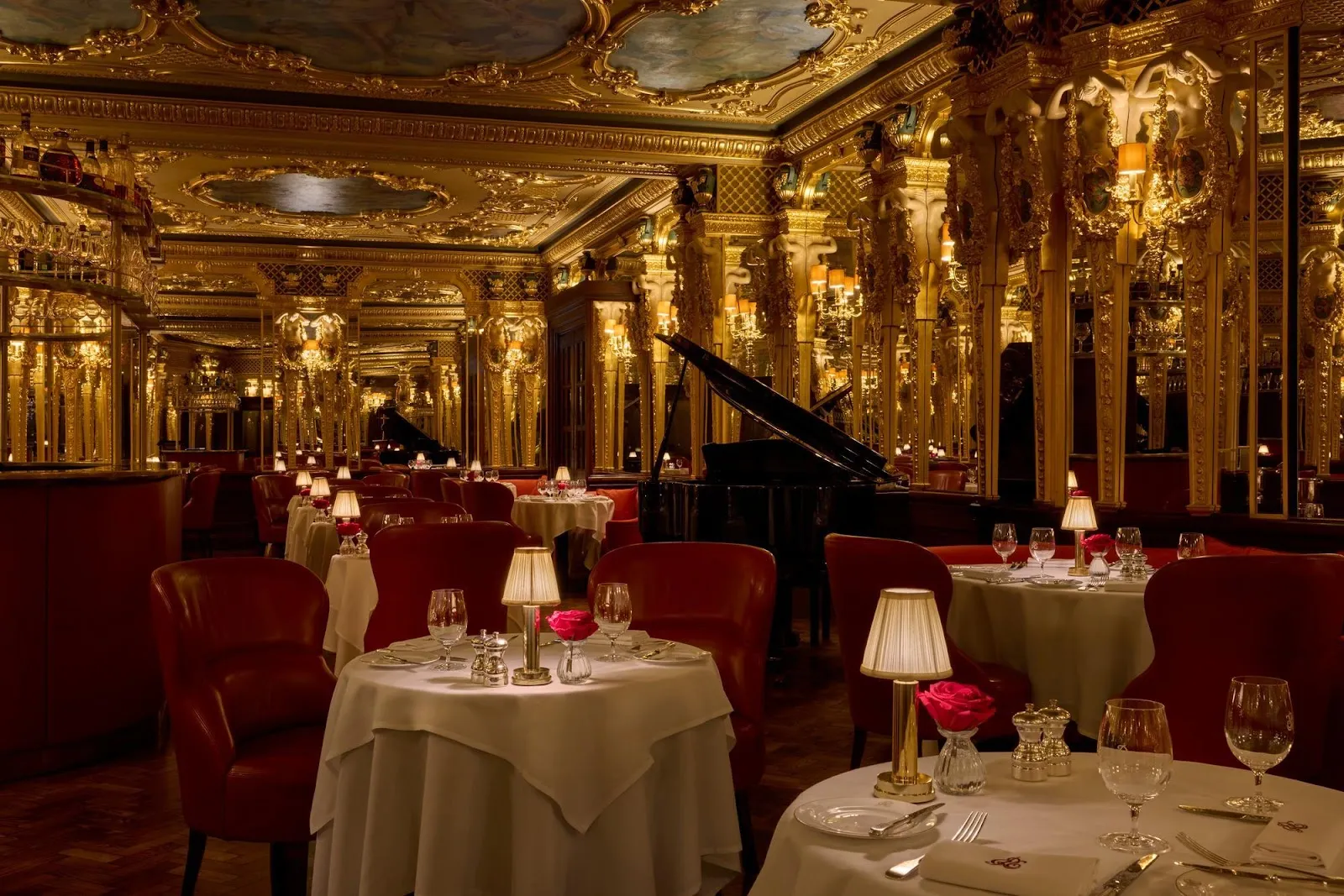 The Grill Room at Hotel Café Royal: a gilded Louis XVI dining room with mirrored walls, a painted ceiling, red leather chairs around white-clothed tables and a grand piano