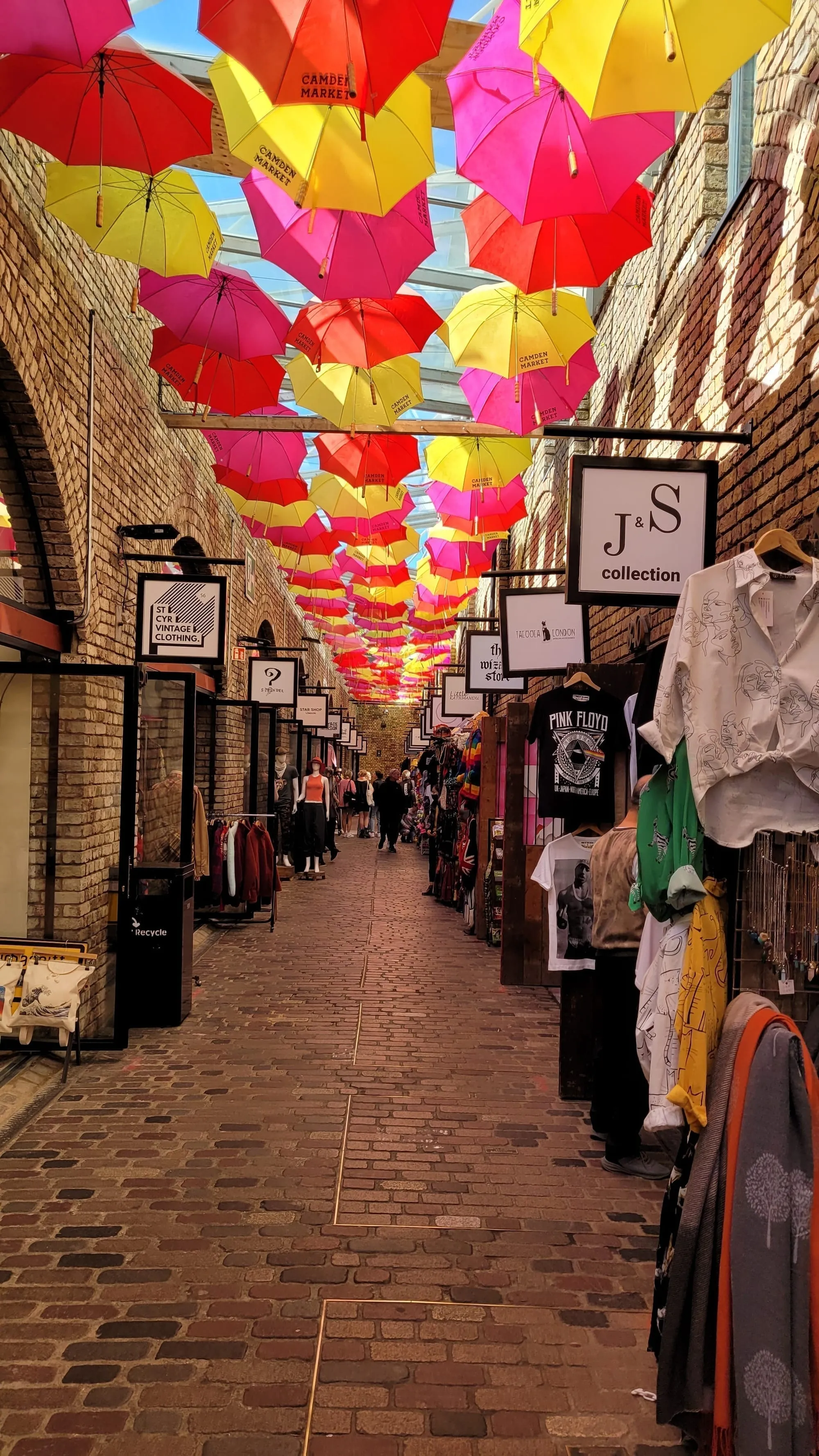 A cobbled alley in Camden Market roofed with hundreds of pink and yellow umbrellas