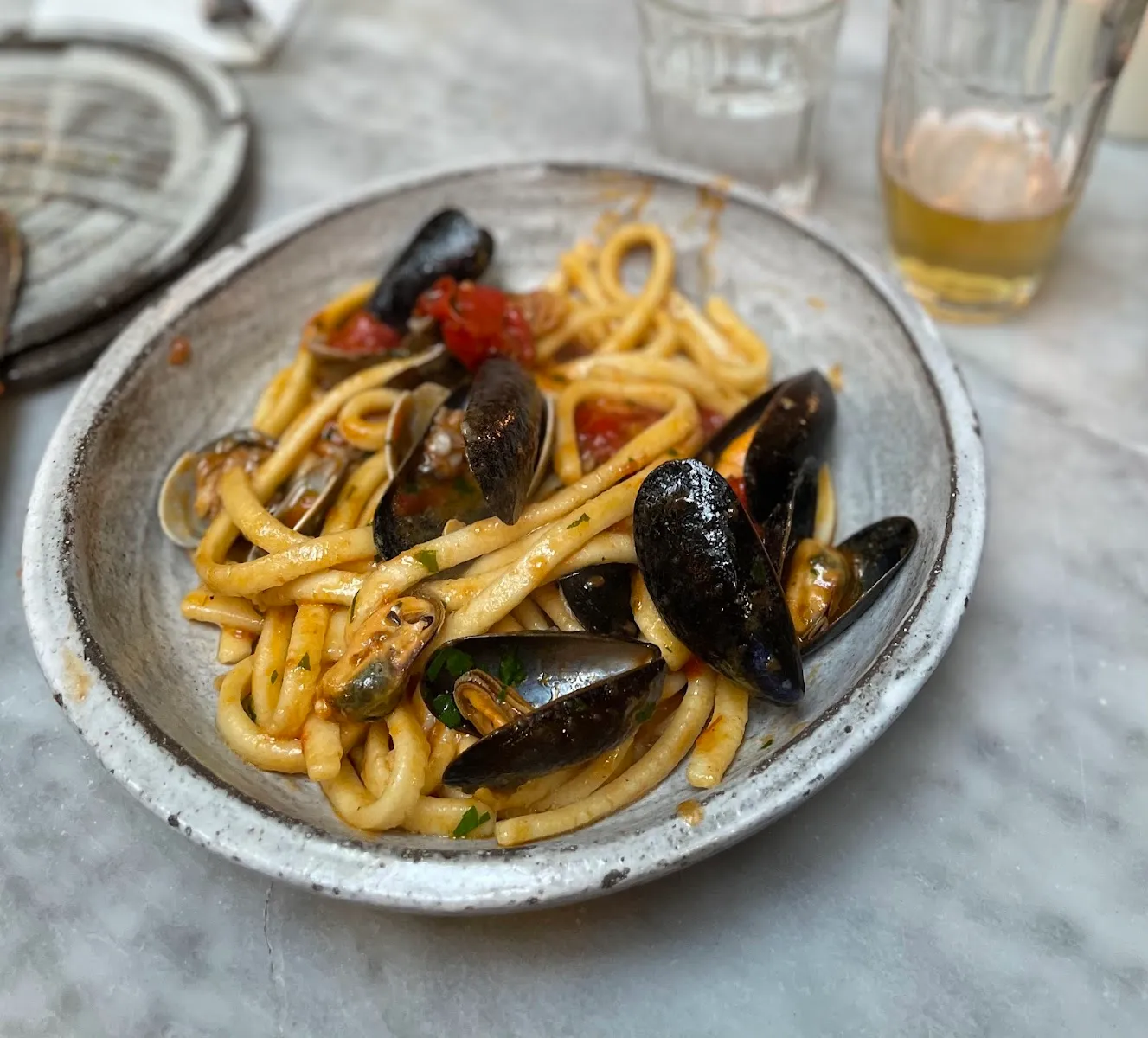 A plate of pasta with clams and mussels in a light tomato sauce