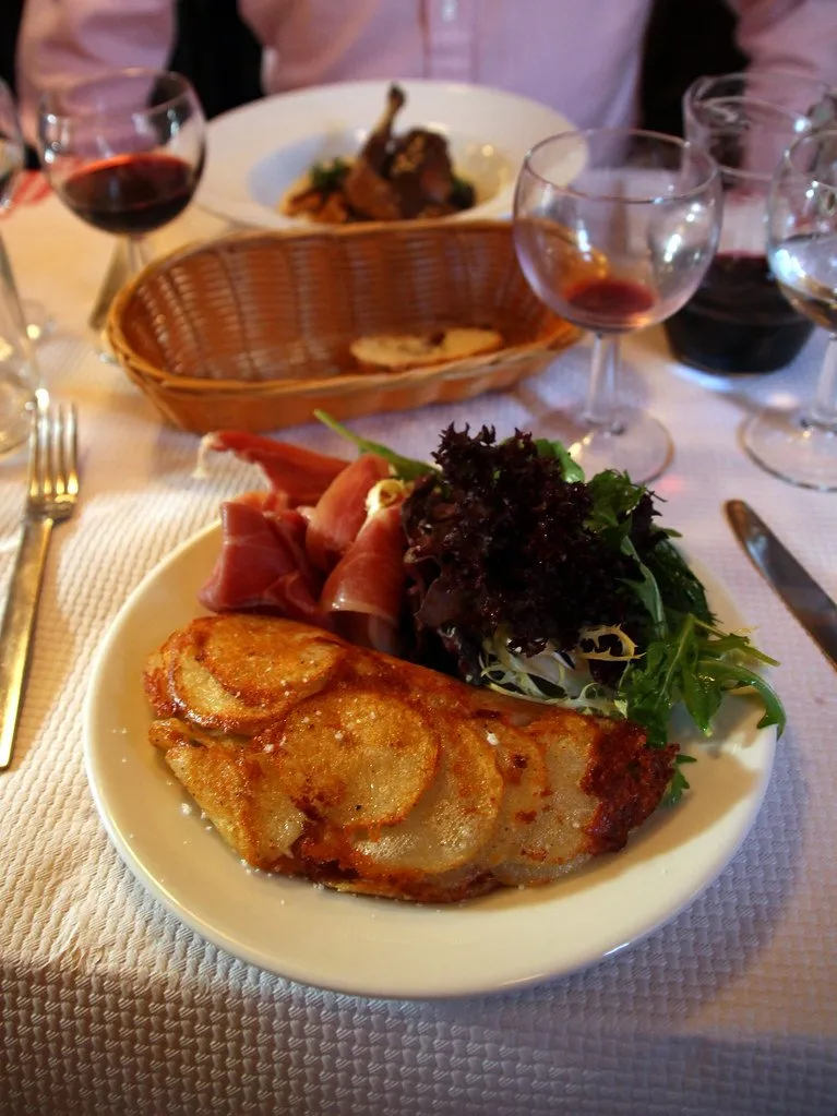 A plate of galette with charcuterie and salad on a checked tablecloth