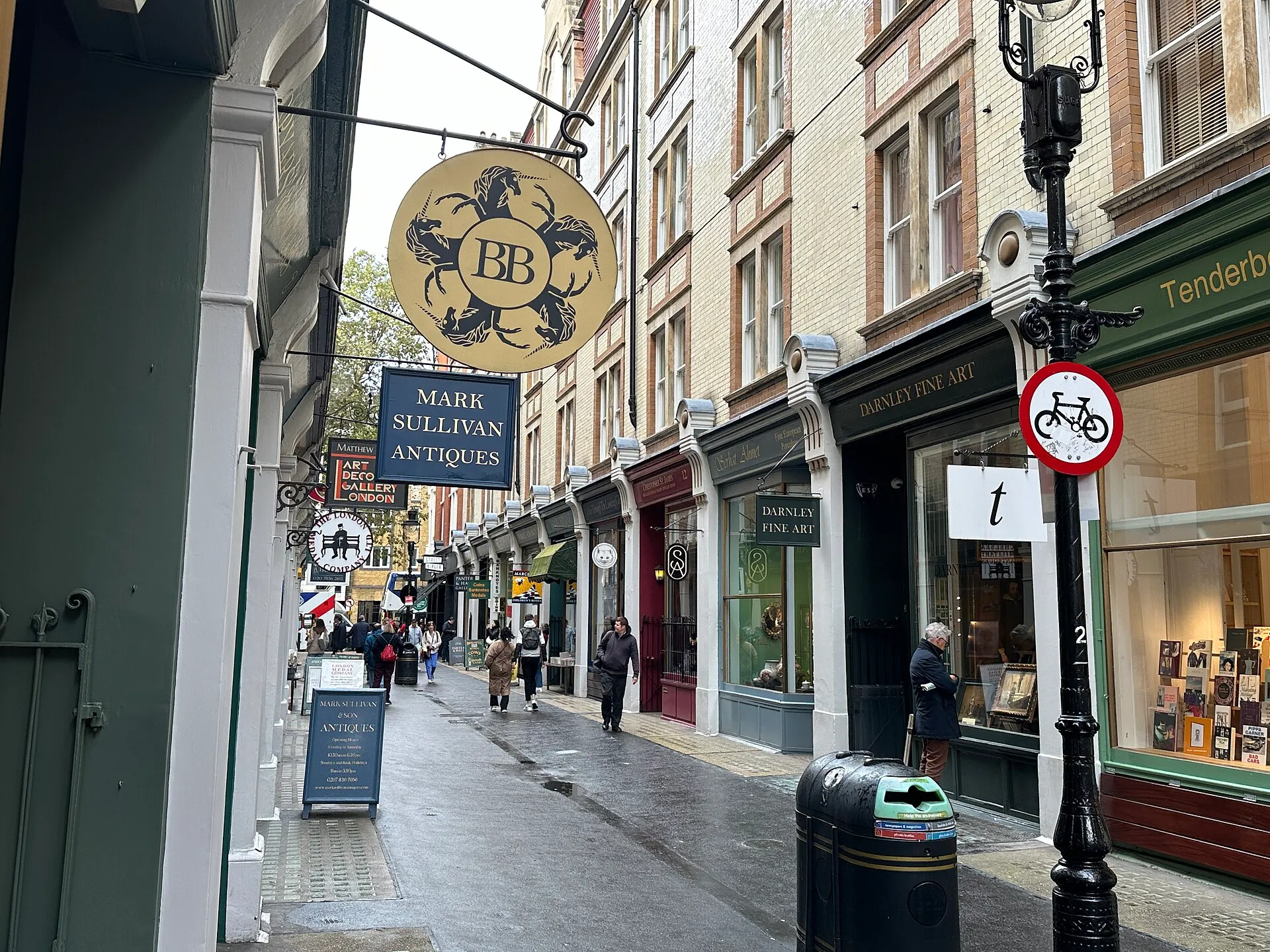 Cecil Court, a narrow pedestrian street of antiquarian shops, with hanging signs for Mark Sullivan Antiques and Darnley Fine Art
