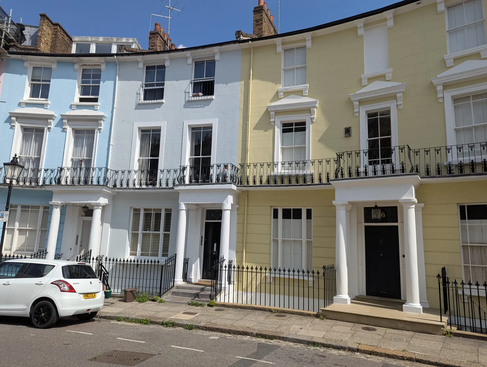 A curving terrace of pastel stucco houses with columned porches on Chalcot Crescent in Primrose Hill