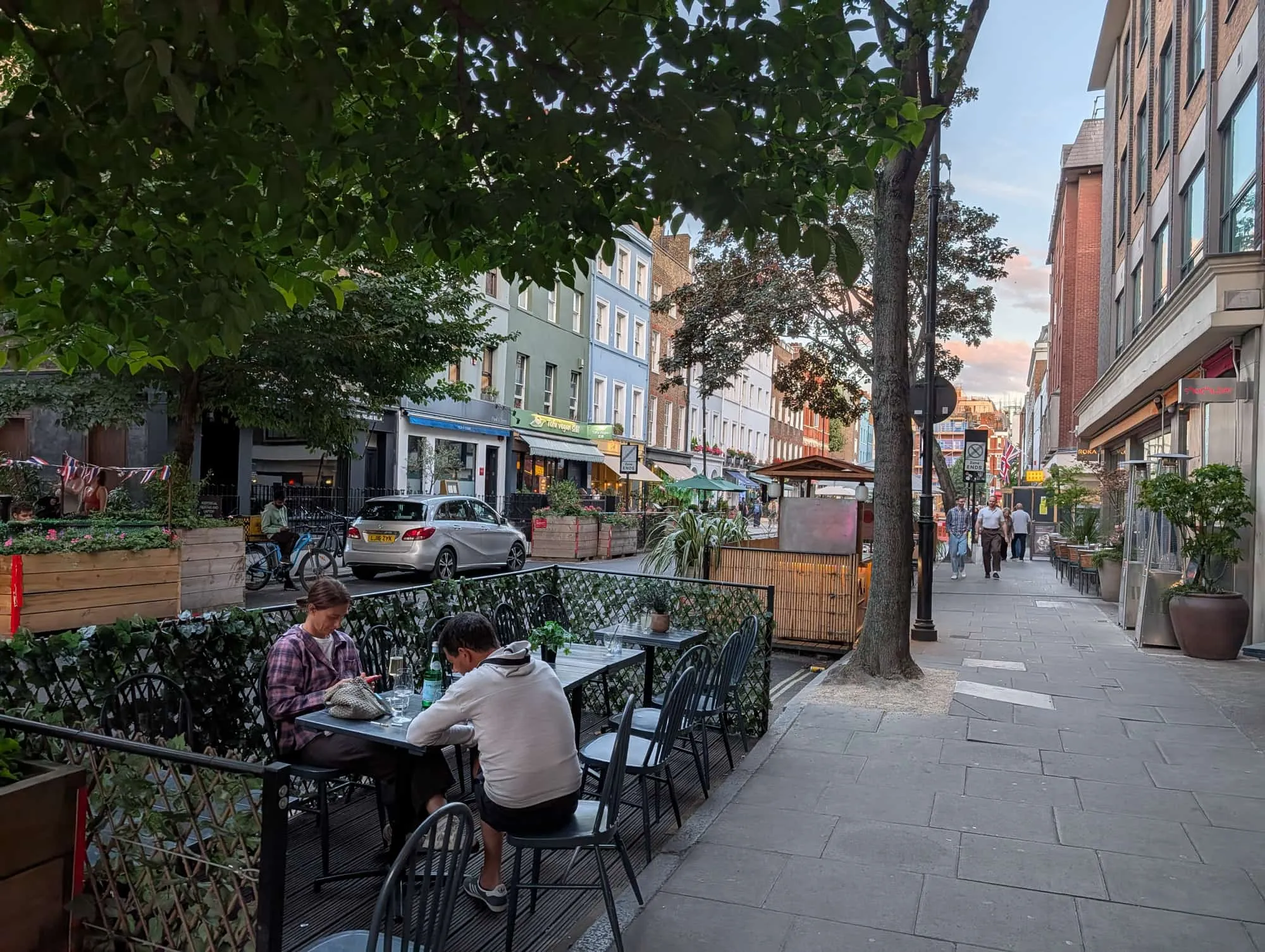 Diners at pavement tables on Charlotte Street in the evening