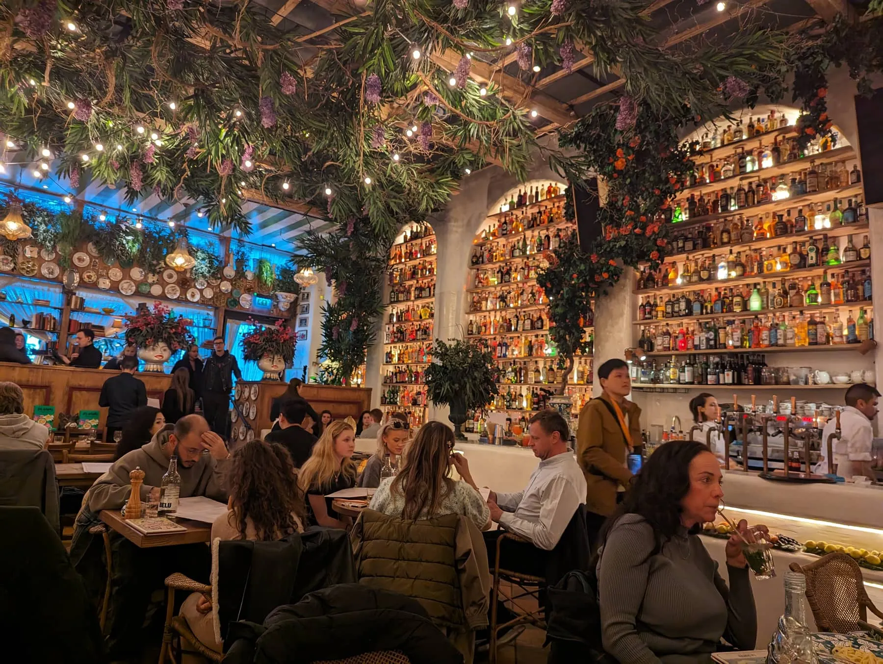 The bar at Circolo Popolare, backed by a wall of bottles beneath hanging greenery